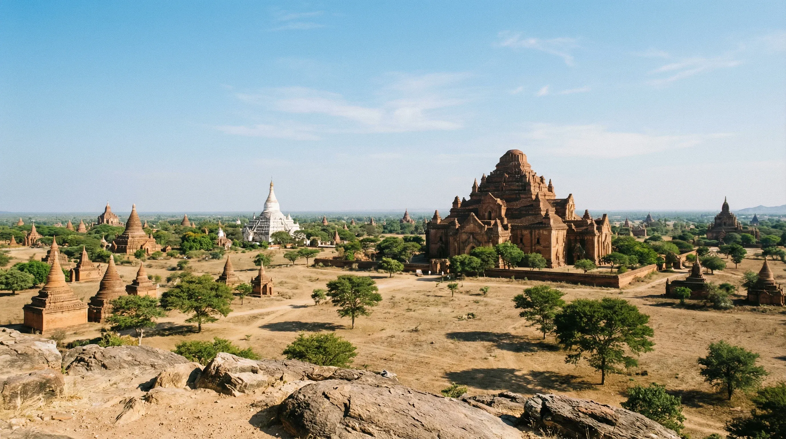 Wide-angle view of ancient red-brick temples and pagodas across the plains of Bagan under a clear sky.