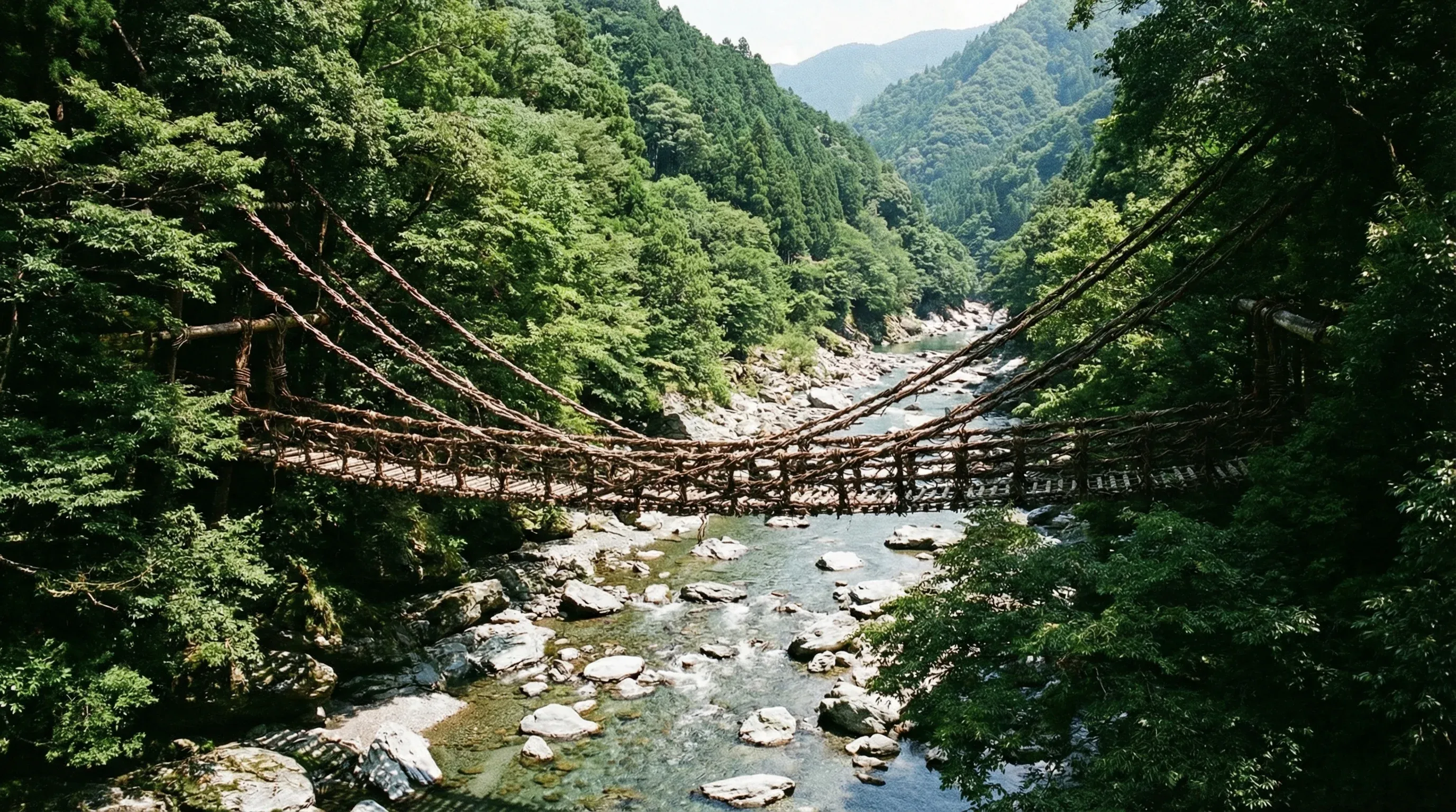 A traditional vine bridge spanning a rocky river in the densely forested Iya Valley.