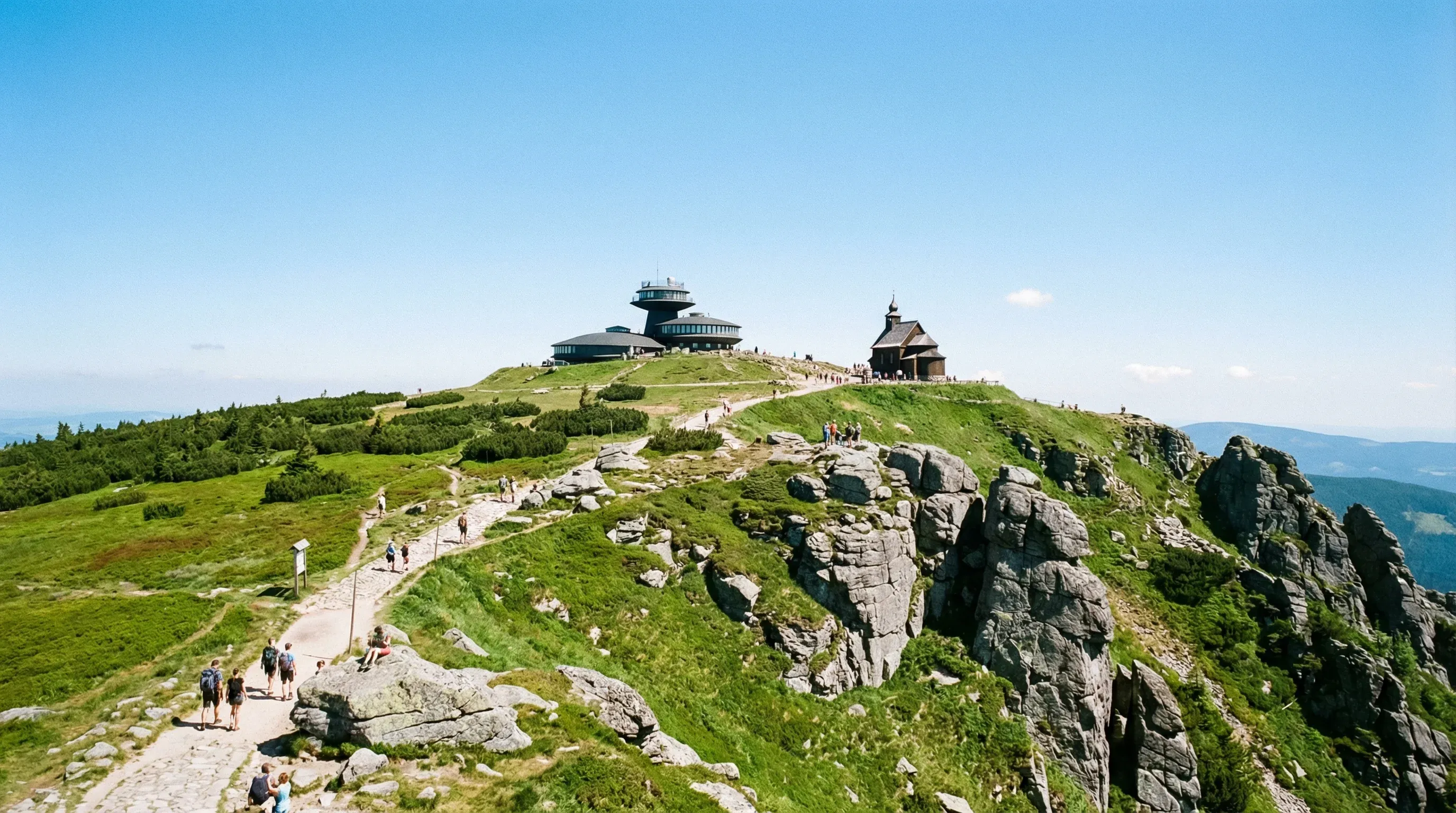 The rounded summit of Mount Sněžka with its unique buildings under a clear blue sky in the Krkonoše Mountains.
