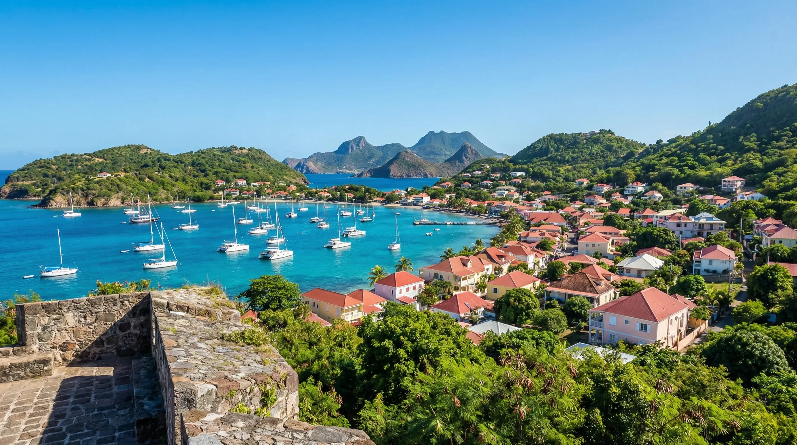 An elevated view of the turquoise Bay of Les Saintes and the red-roofed buildings of Terre-de-Haut village in Guadeloupe.