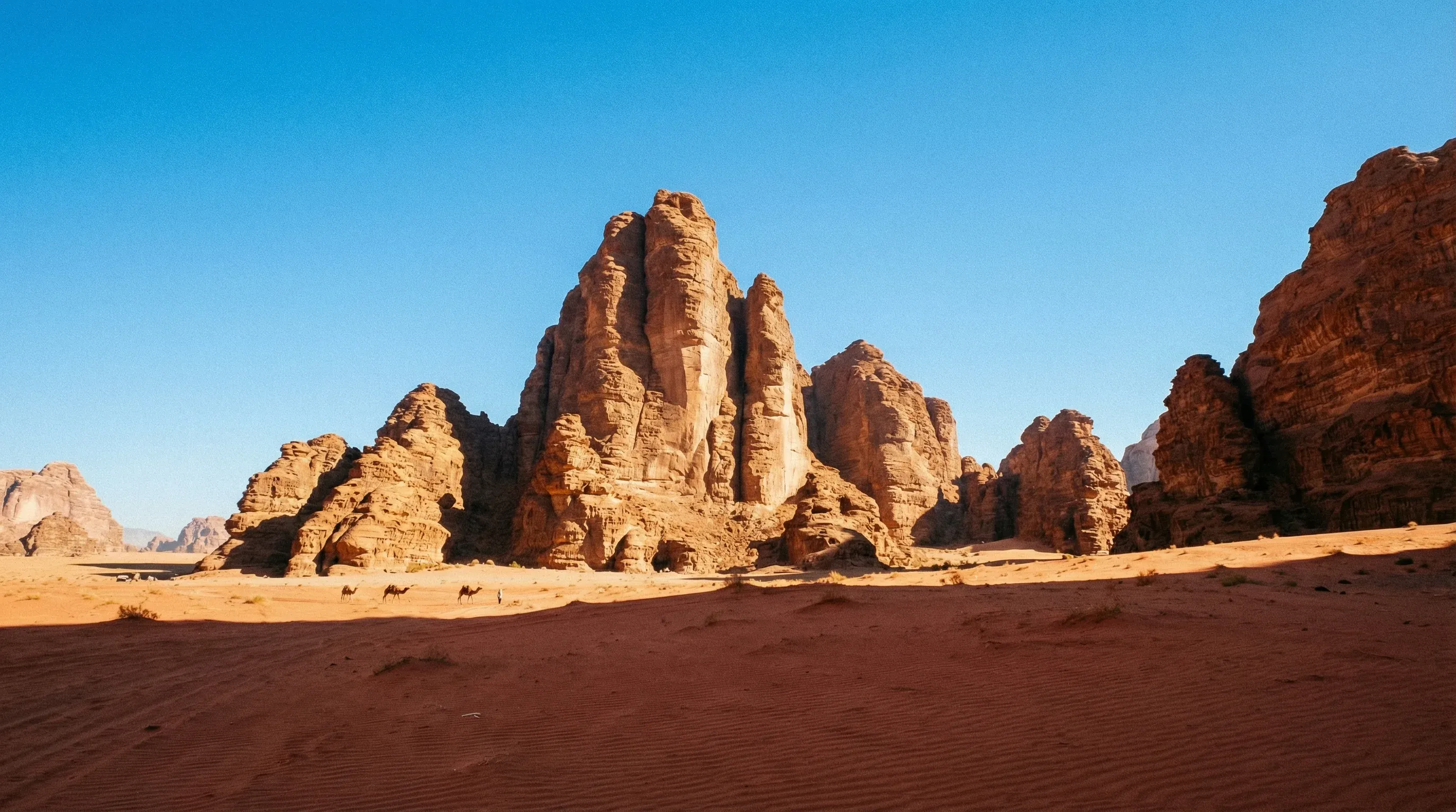 The massive sandstone formation known as the Seven Pillars of Wisdom rises from the red desert sand of Wadi Rum in southern Jordan.