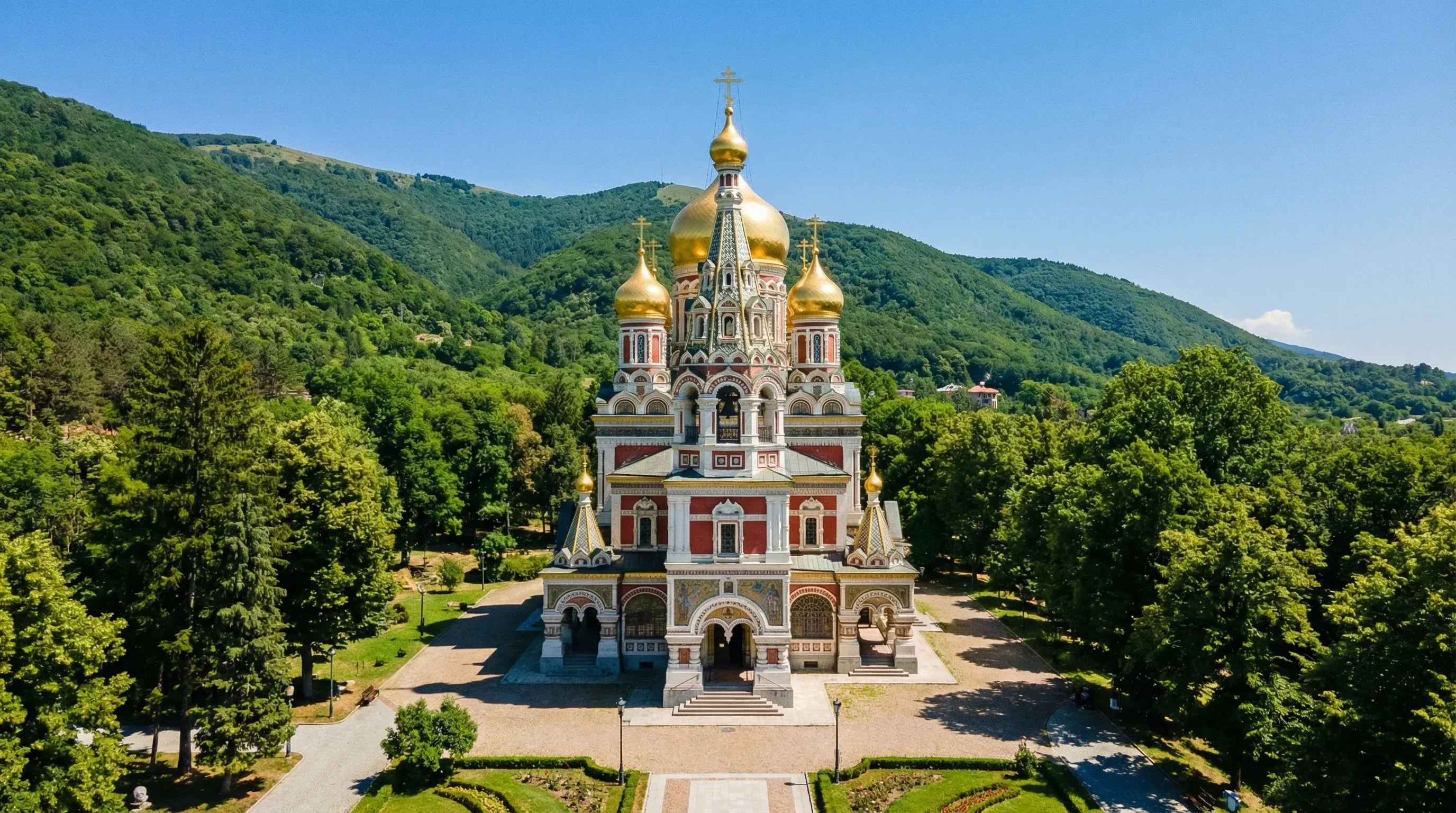 The Shipka Memorial Church with its golden domes and red-and-white facade, situated at the base of the Balkan Mountains in Bulgaria.