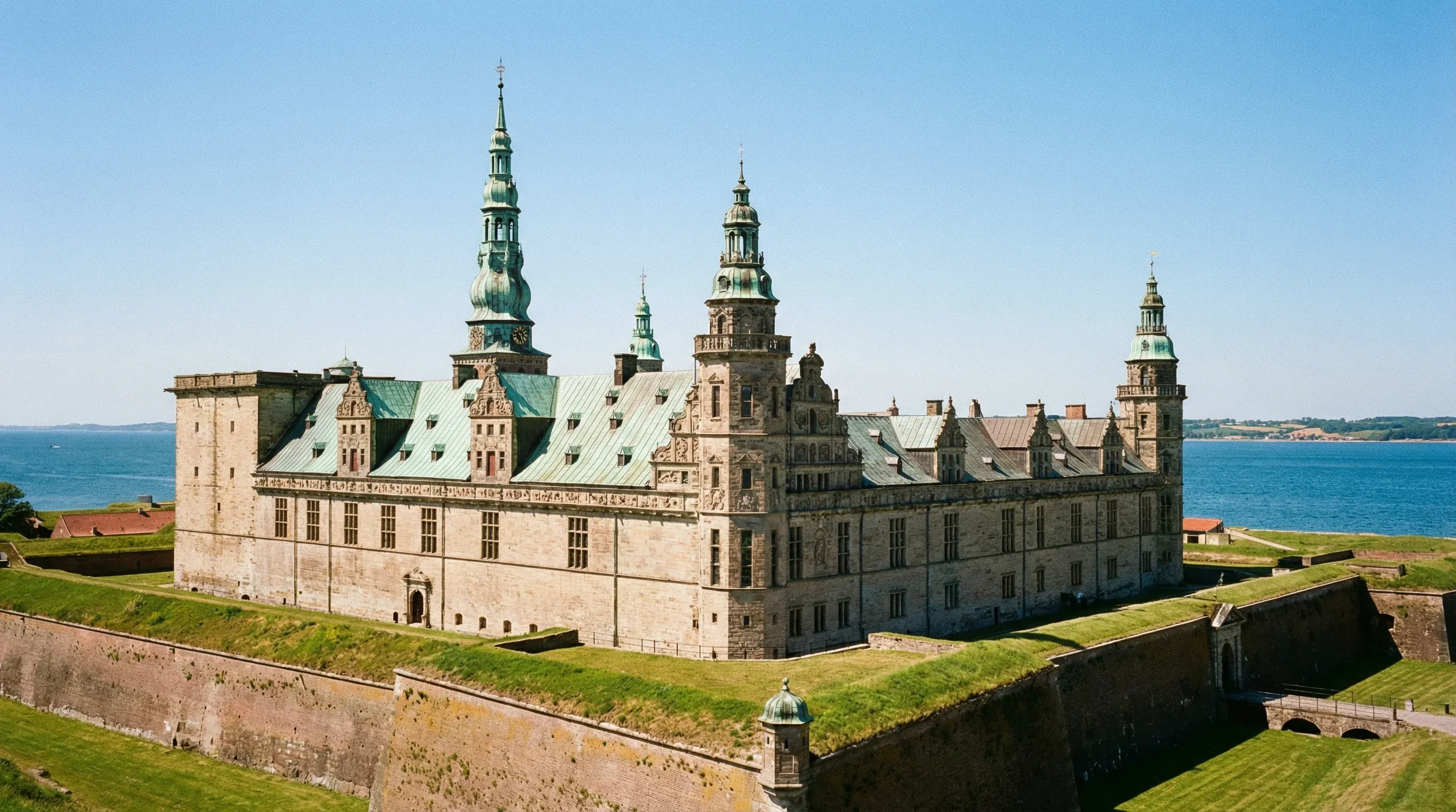 The Renaissance-style Kronborg Castle with its copper-green roofs and stone walls next to the sea.
