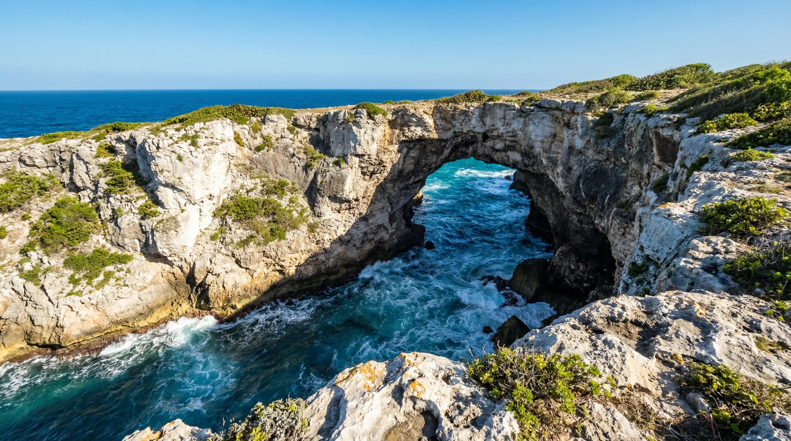 A view looking down into the Gueule Grand Gouffre natural sea arch and the turquoise ocean water in Marie-Galante, Guadeloupe.