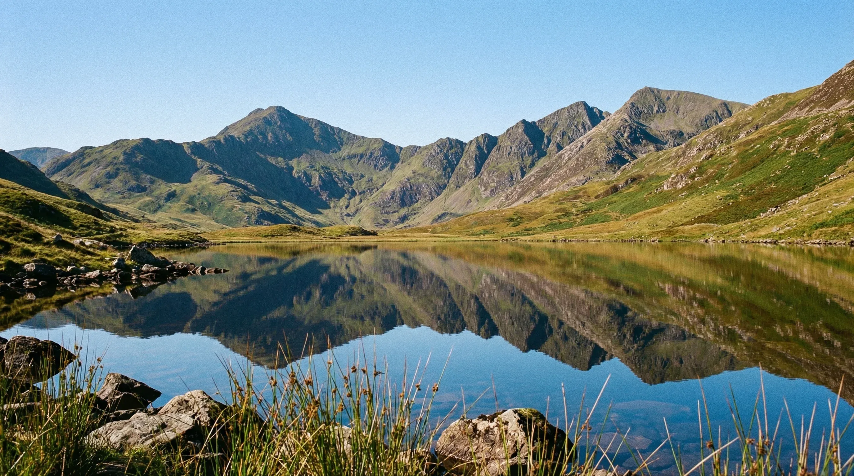 The mountain peaks of Snowdon reflected in a lake in the Eryri National Park in North Wales on a sunny day.