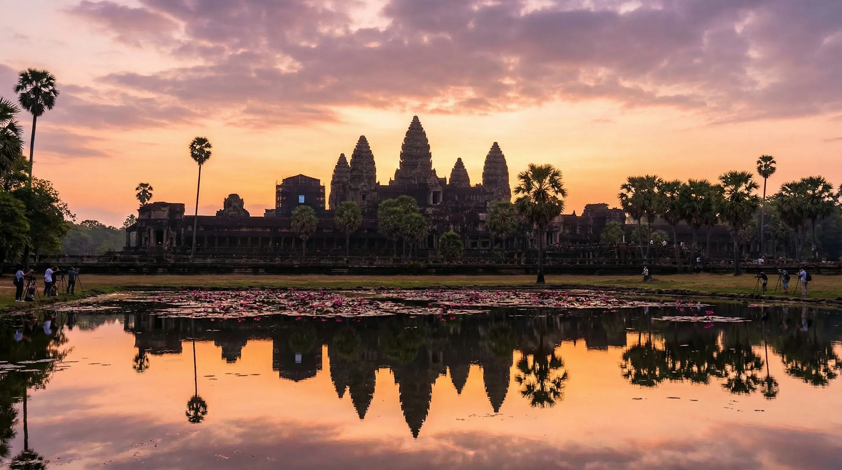 The five towers of Angkor Wat temple reflected in a calm pond during a colorful sunrise in Siem Reap.