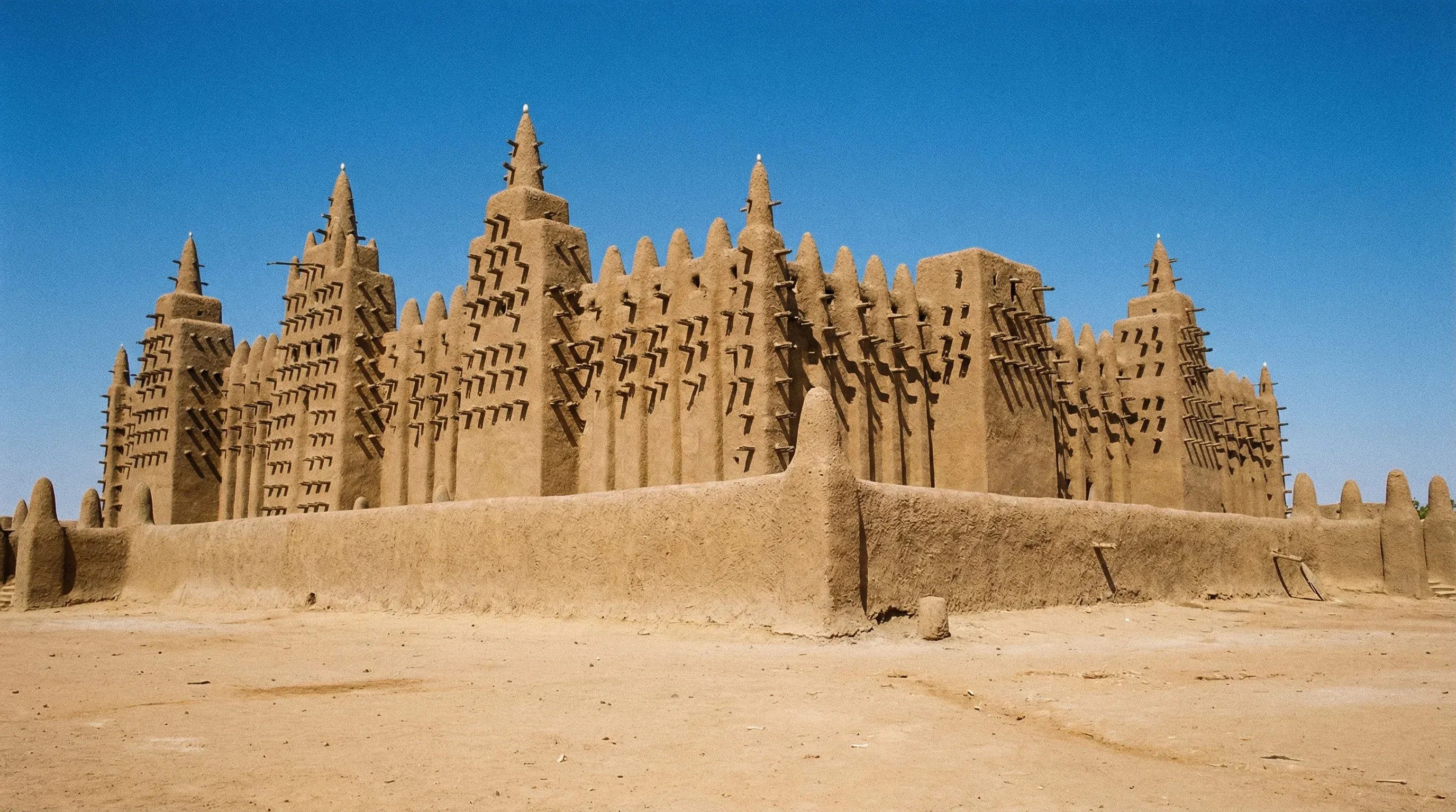 The Great Mosque of Djenné in Mali, a massive Sudano-Sahelian mud-brick building under a clear blue sky.