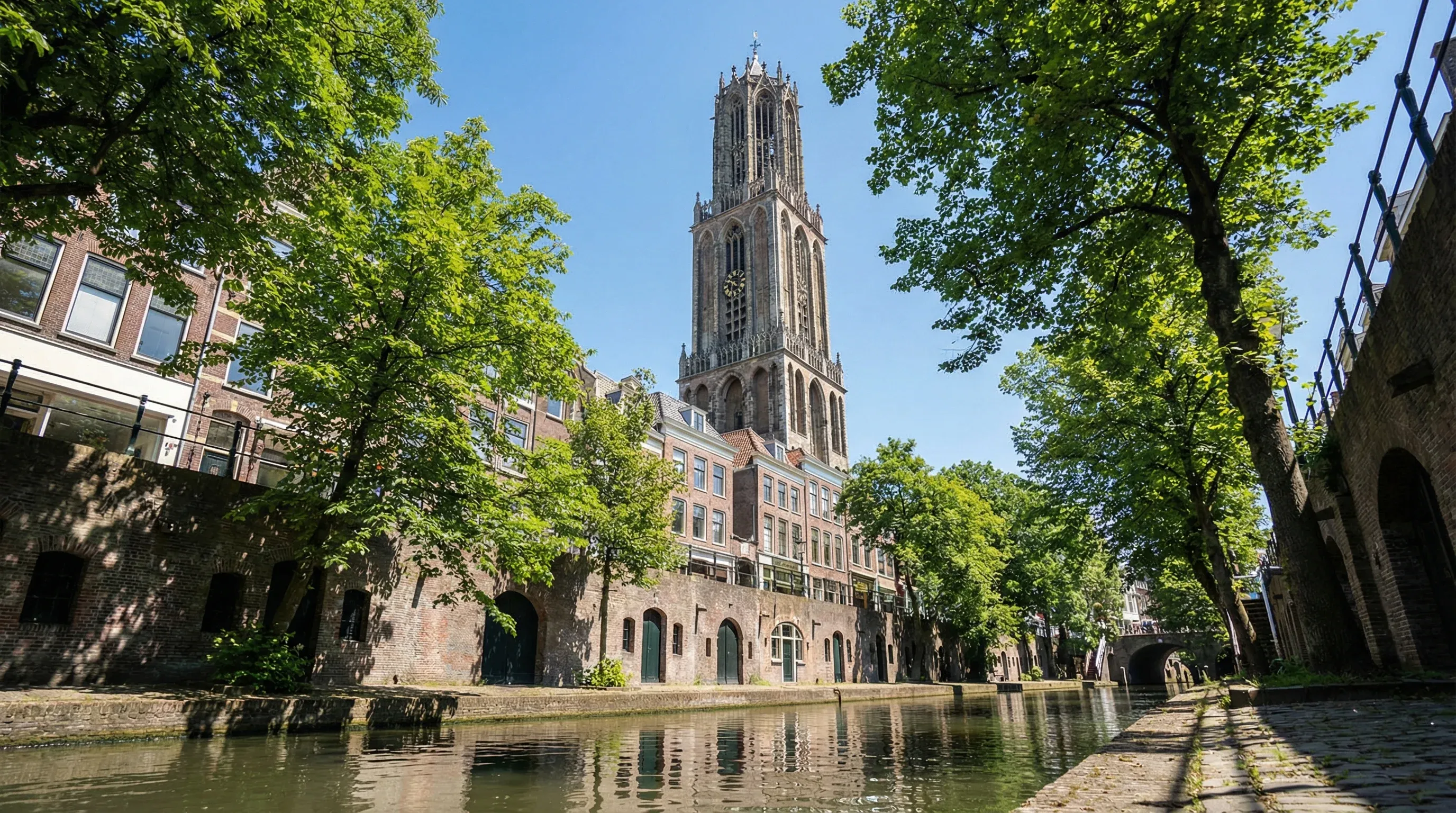 The Gothic Dom Tower of Utrecht rising above the canal-side buildings and the Oudegracht.