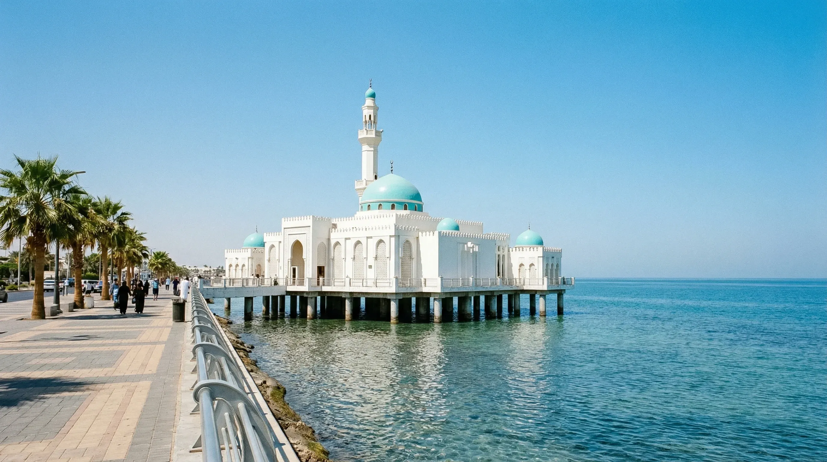 A white mosque with a large dome built over the Red Sea on the Jeddah waterfront.