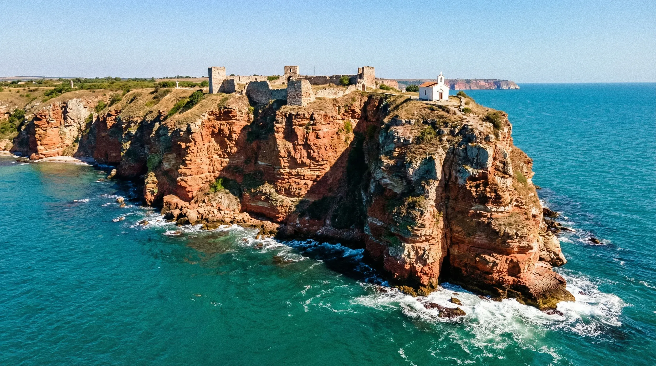 Red limestone cliffs of Cape Kaliakra extending into the Black Sea in Northeast Bulgaria, featuring ruins of an ancient fortress.