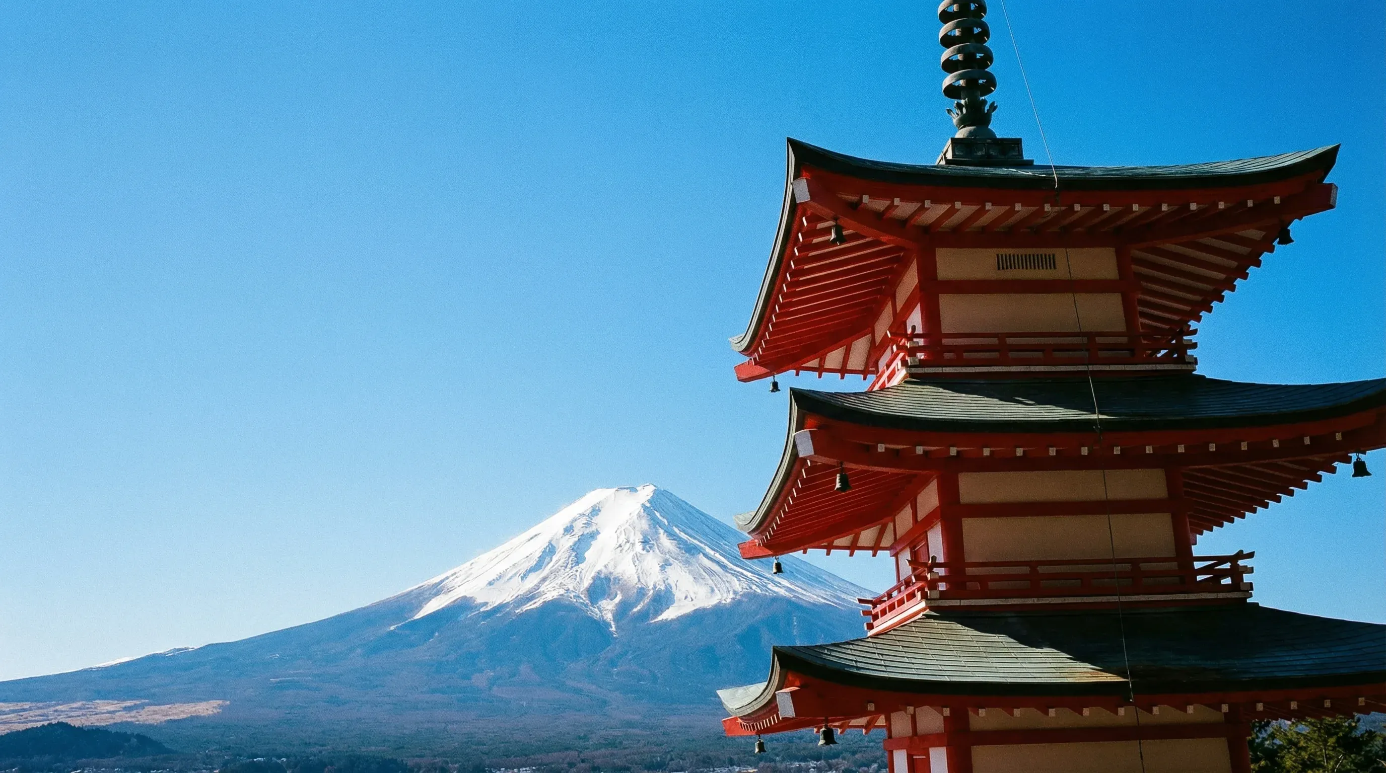The red Chureito Pagoda in the foreground with the snow-capped peak of Mount Fuji in the background.
