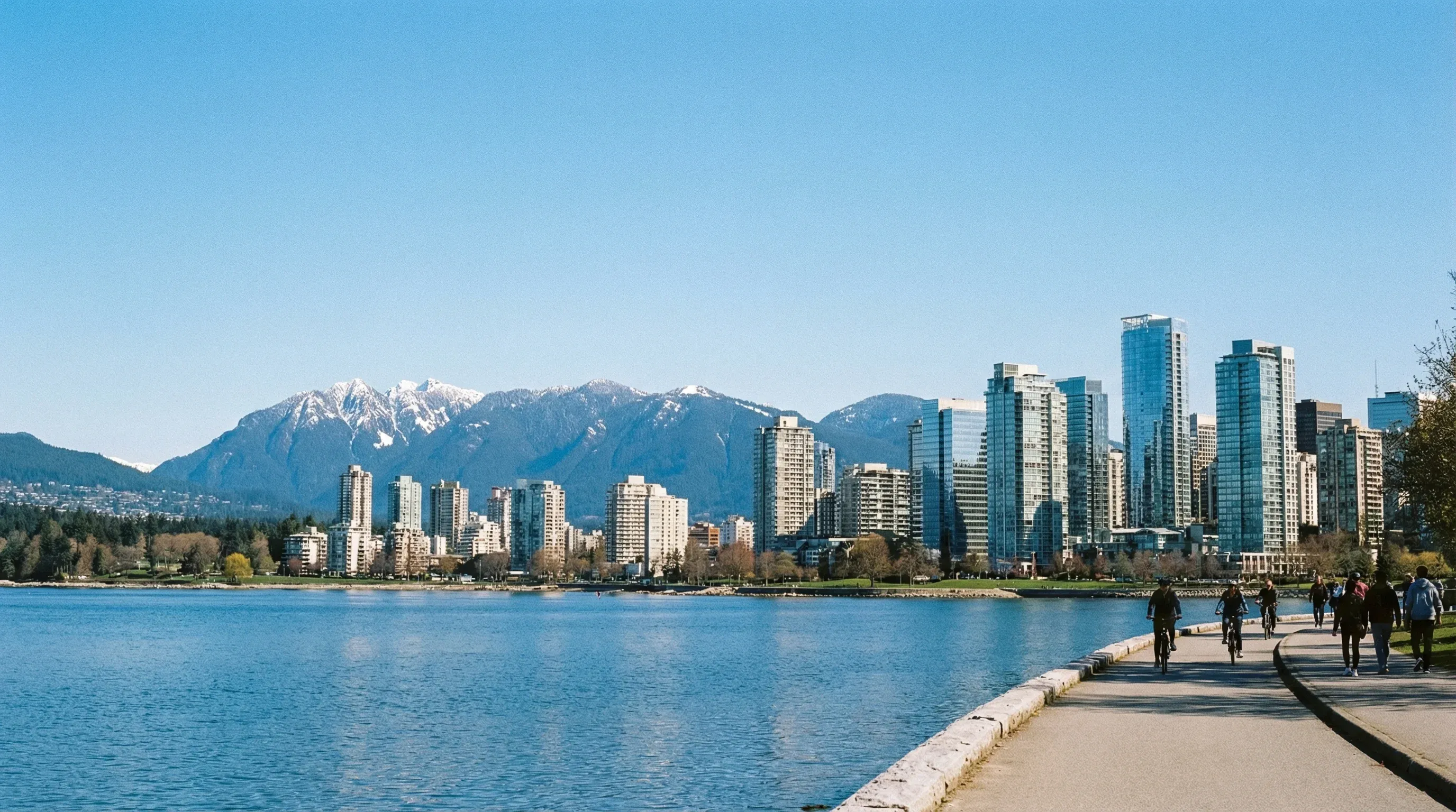 The Vancouver city skyline and the snow-capped North Shore Mountains viewed from Stanley Park across the water.