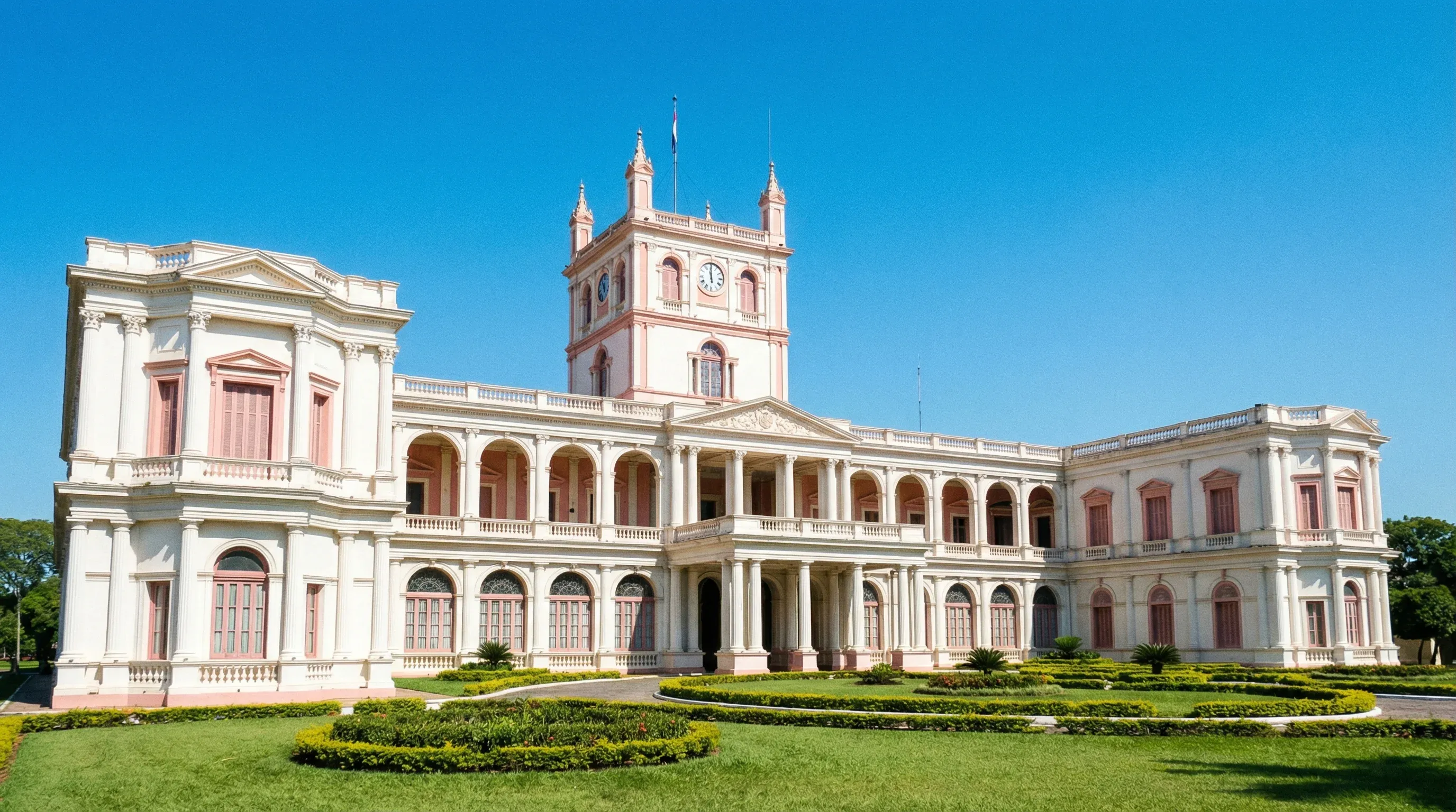 A white neoclassical government palace with a central tower and green gardens in Asunción, Paraguay.