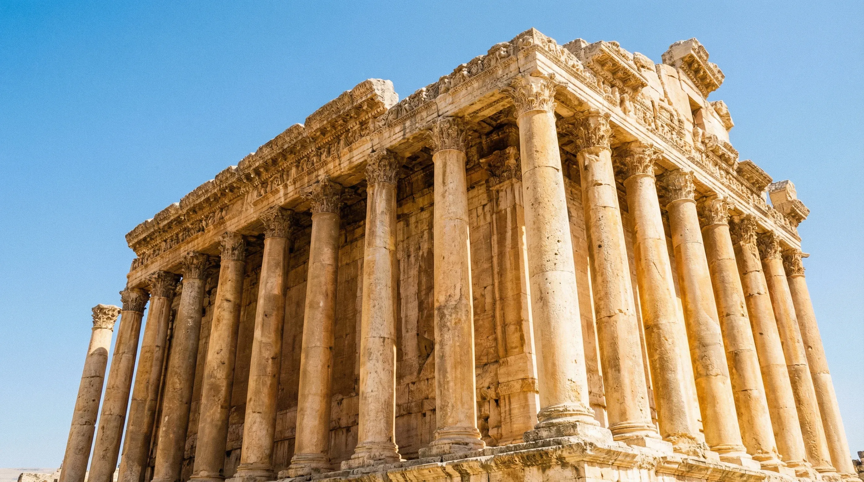 The ancient Roman Temple of Bacchus in Baalbek, showing its tall stone columns and detailed carvings under a clear sky.