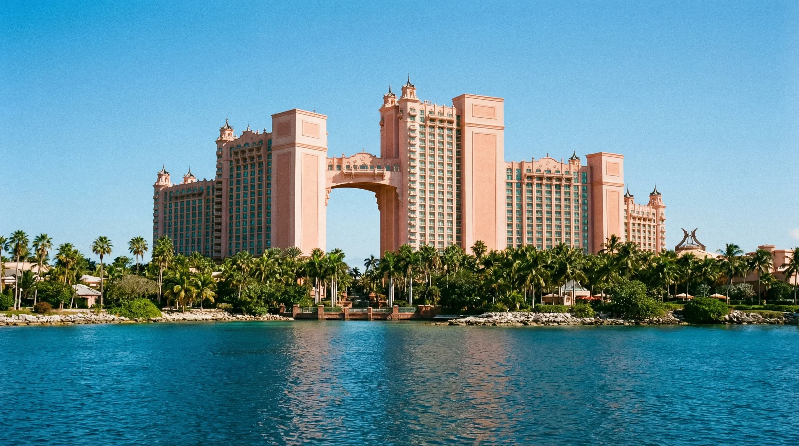 The iconic coral-pink Royal Towers of Atlantis on Paradise Island, viewed from the water under a clear sky.