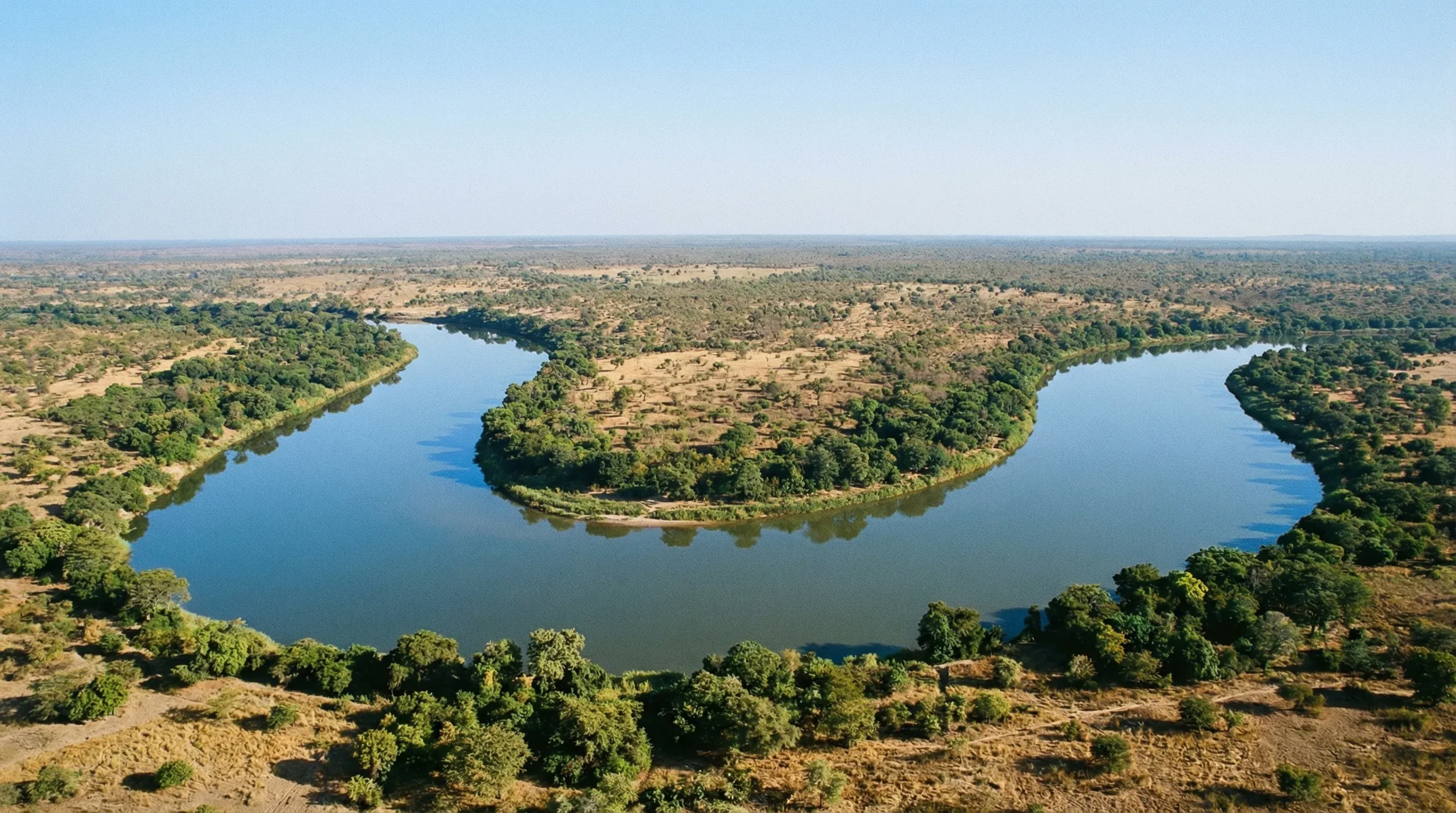 An aerial view of the Niger River as it bends in a W-shape through the savanna and green forests of W National Park.