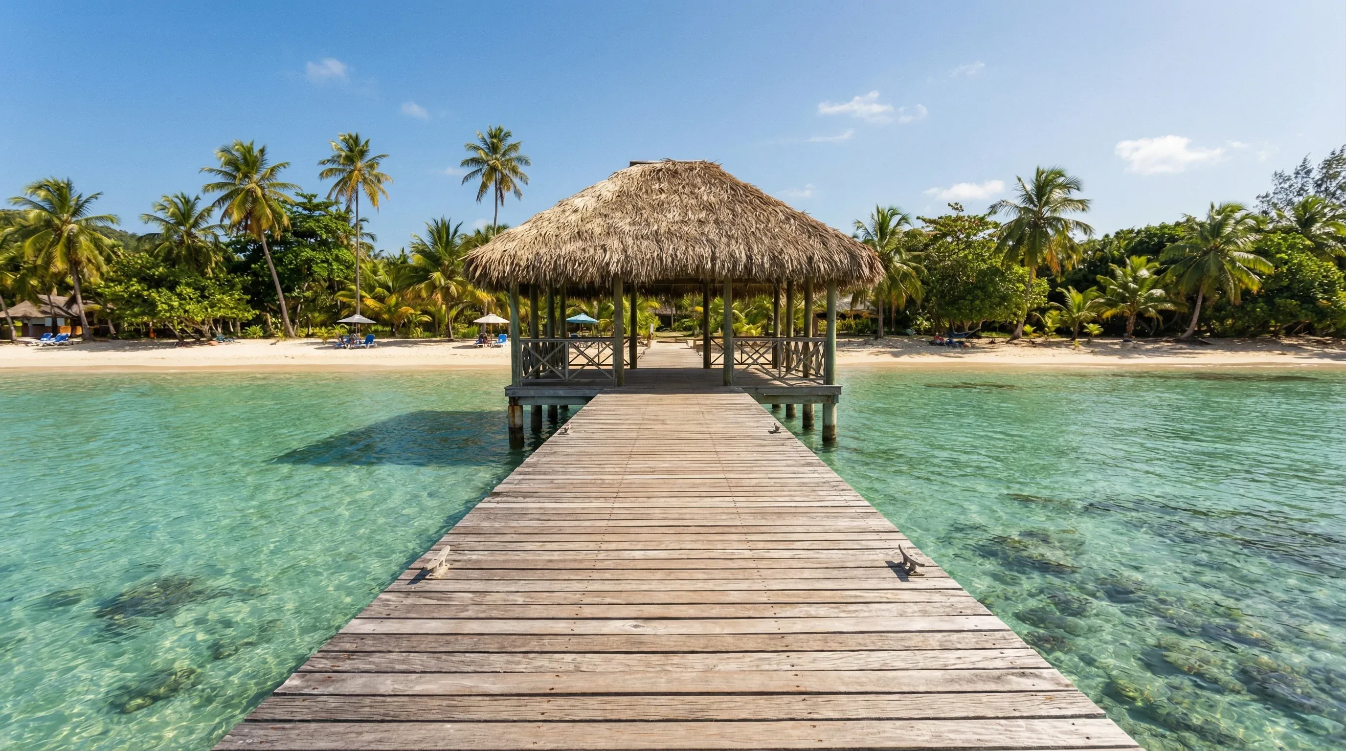 A wooden pier with a traditional thatched-roof hut extending into turquoise Caribbean waters at Pigeon Point, Tobago.