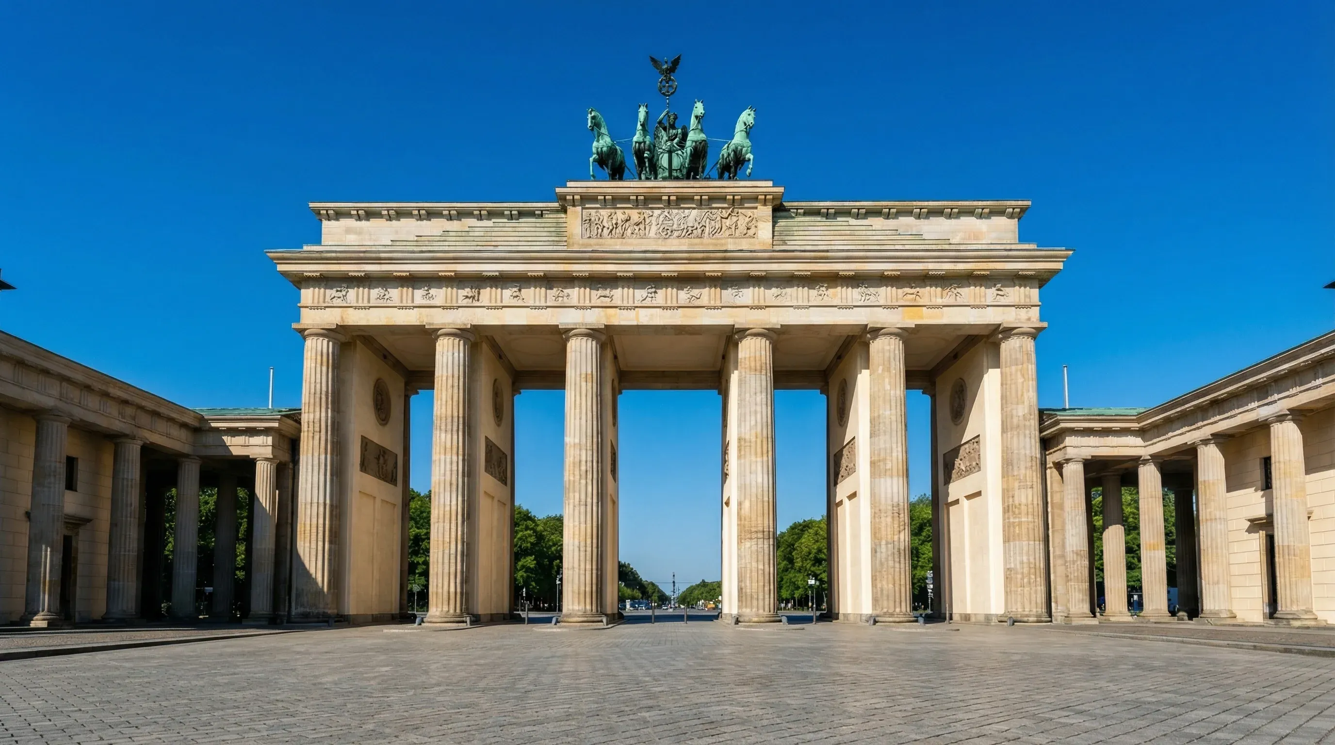 The neoclassical Brandenburg Gate stands prominently under a clear blue sky in central Berlin.