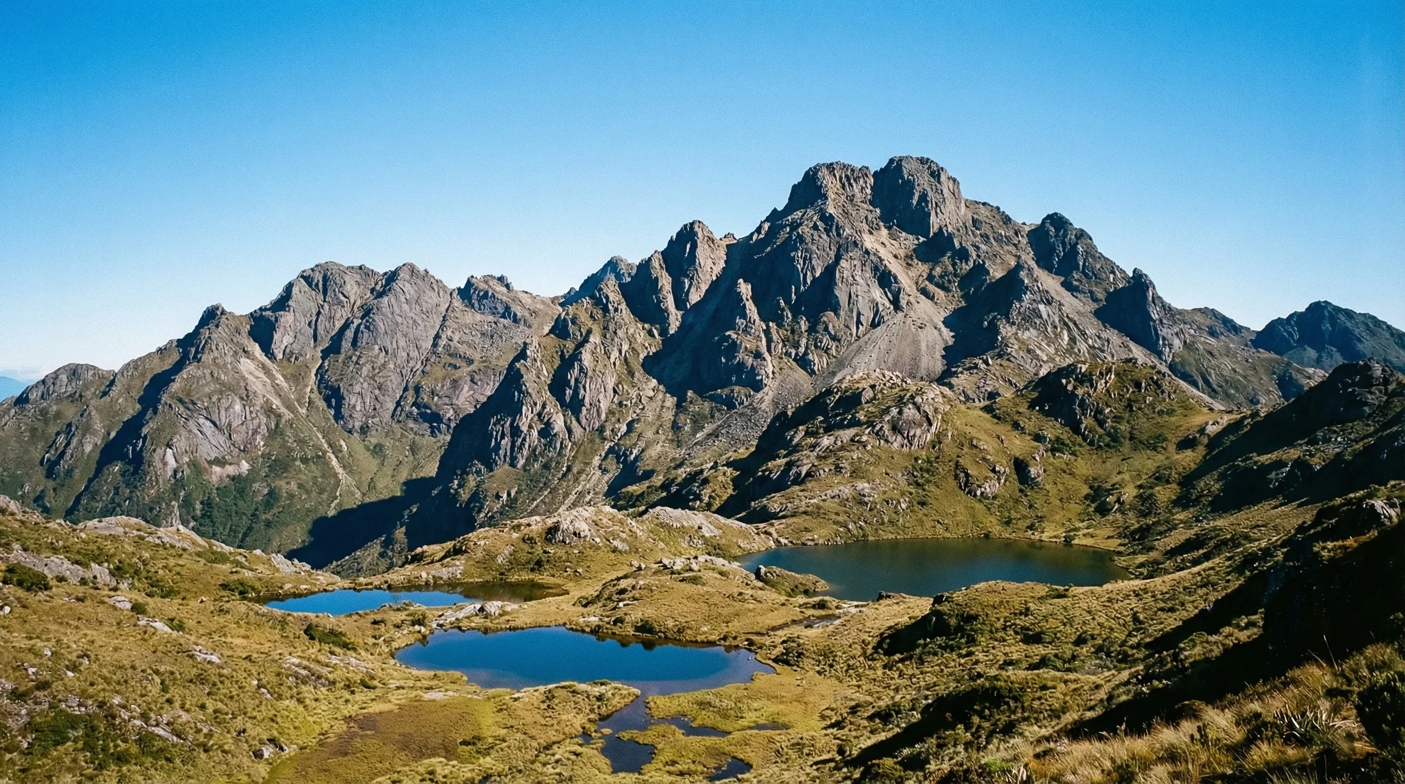 A wide-angle view of the rocky peaks of Mount Wilhelm rising above alpine valleys and glacial lakes in the Highlands of Papua New Guinea.
