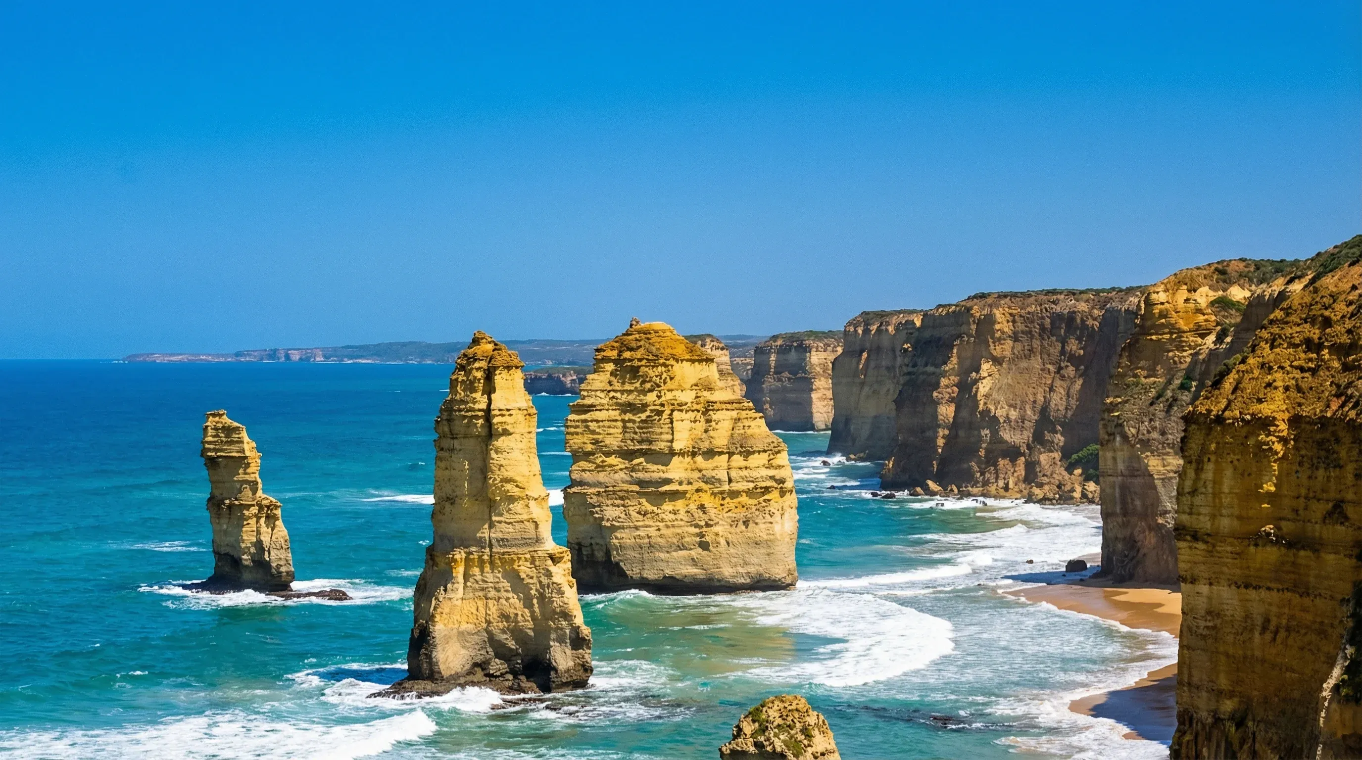 Massive limestone stacks known as the Twelve Apostles standing in the turquoise ocean along the Victorian coastline.