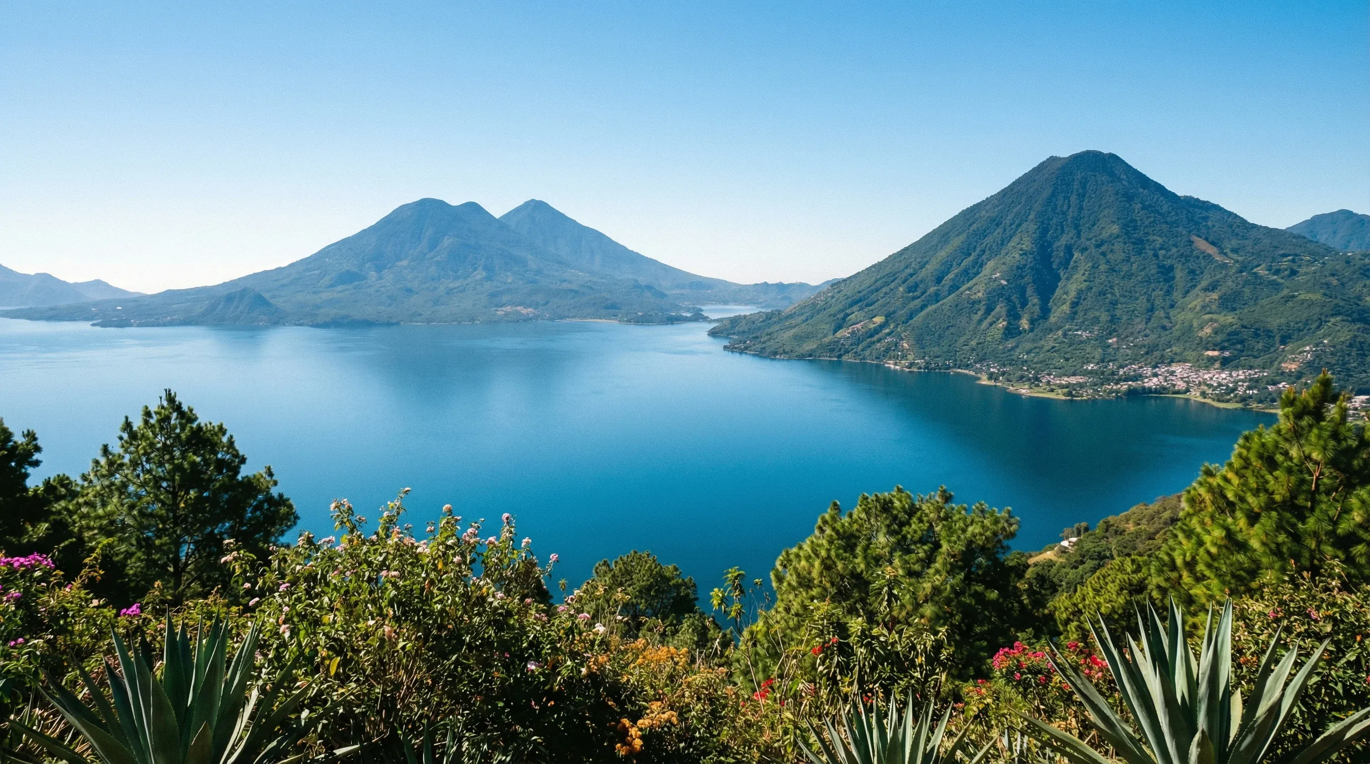 An elevated view of the blue water of Lake Atitlán surrounded by three large volcanoes in the Guatemalan Highlands.