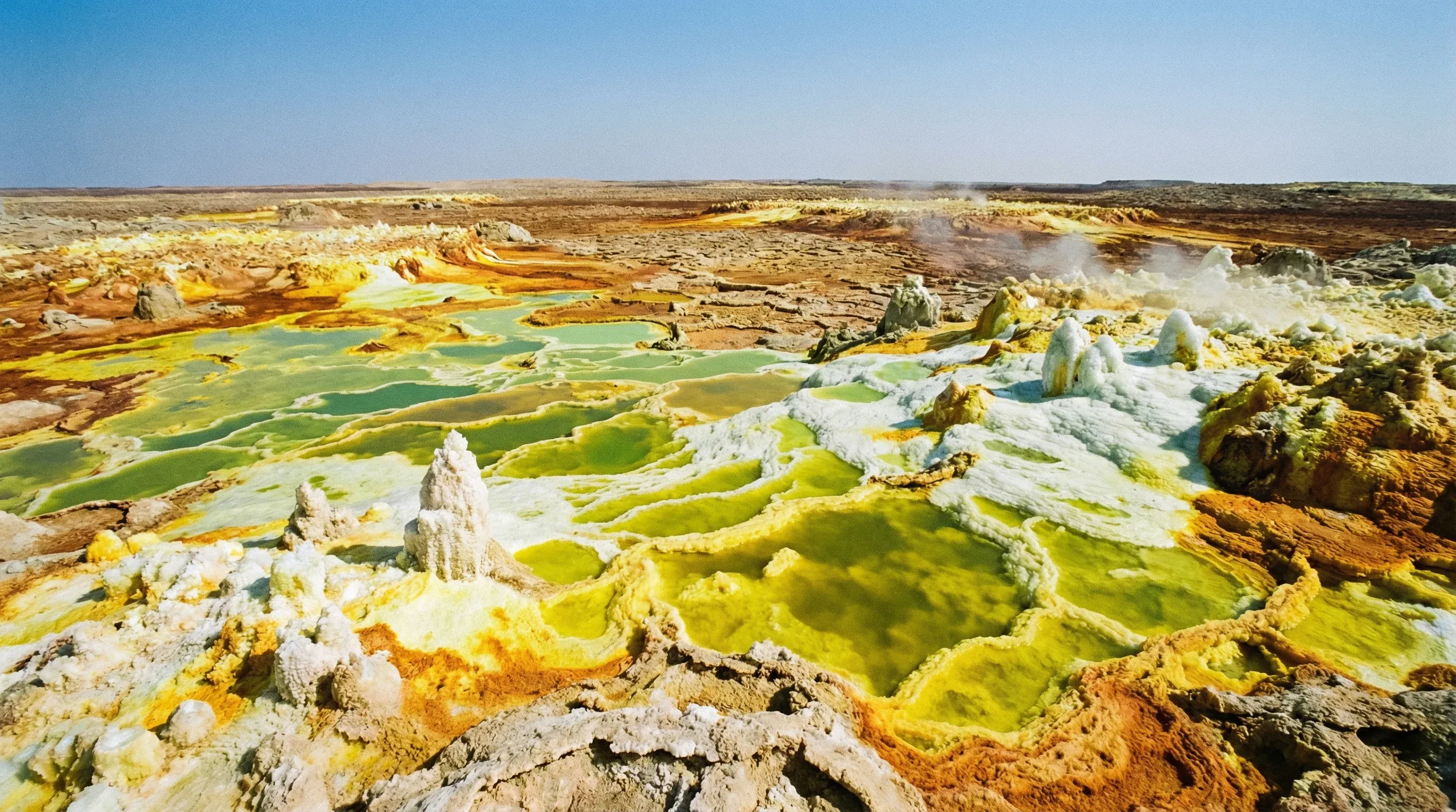 Vibrant yellow and green mineral deposits and white salt formations at the Dallol hydrothermal field in the Danakil Depression.