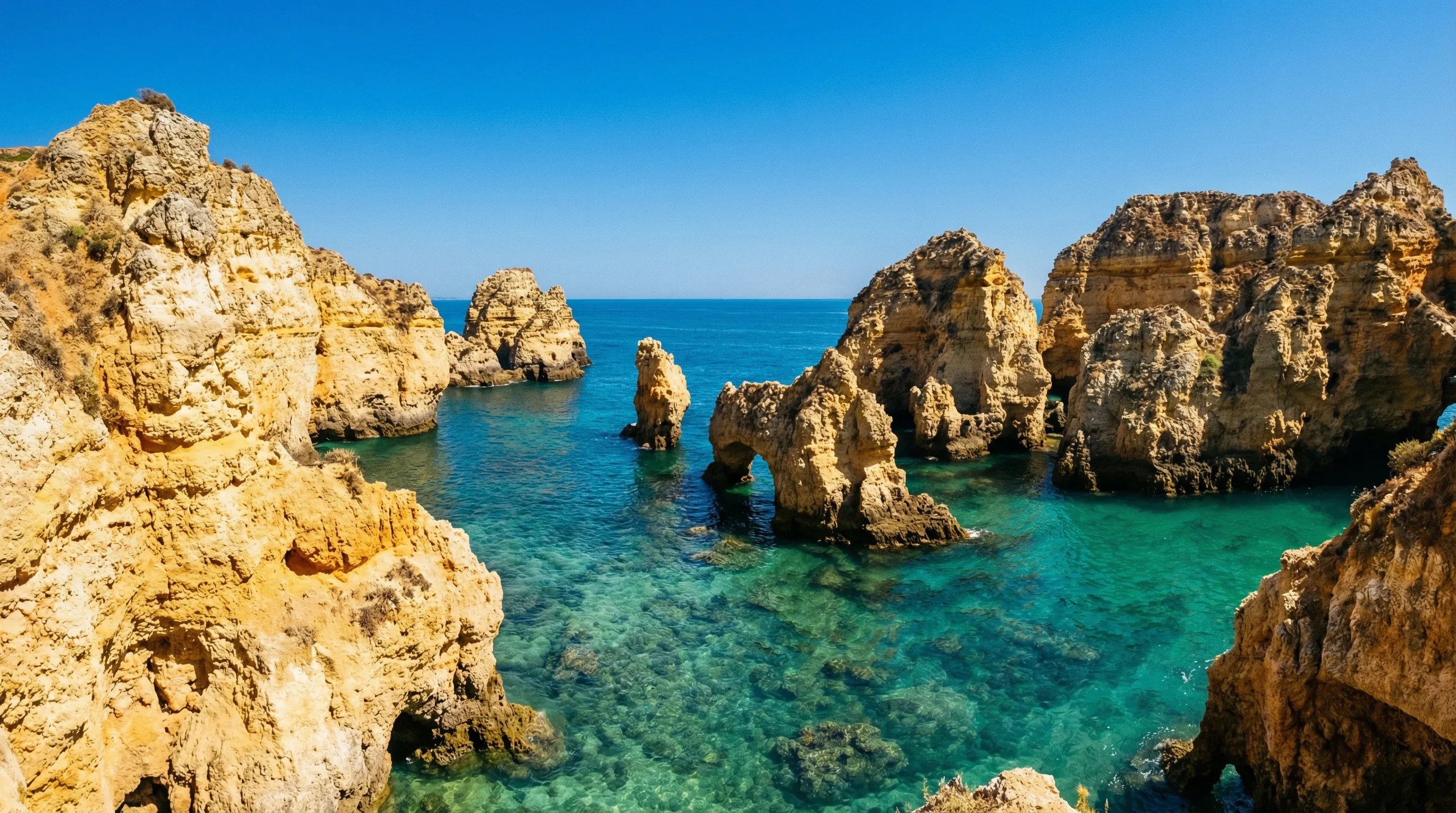 Golden rock formations and sea arches of Ponta da Piedade in Lagos, Algarve, surrounded by turquoise water.
