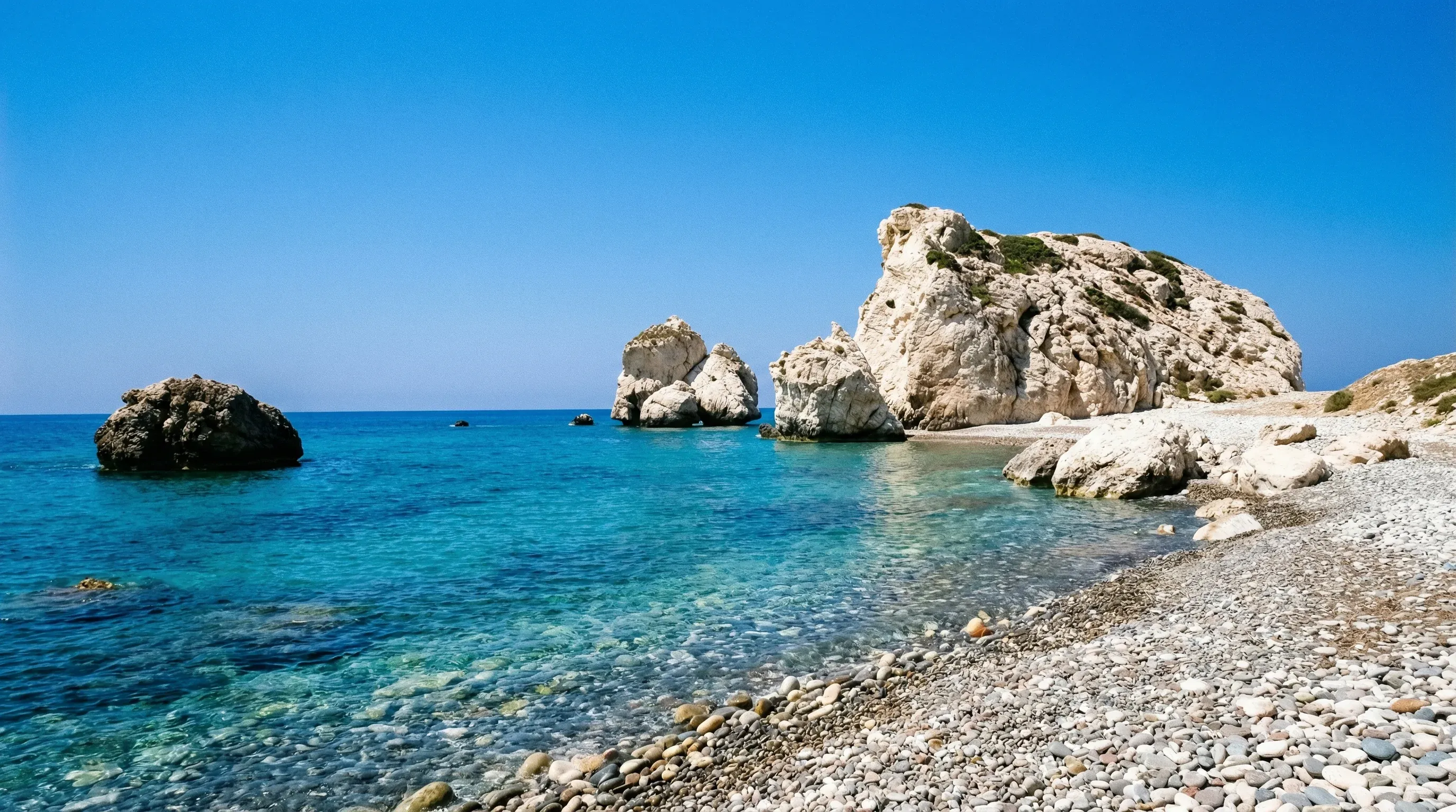 Large white limestone sea stacks known as Aphrodite's Rock standing in the clear blue sea off the Paphos coast.
