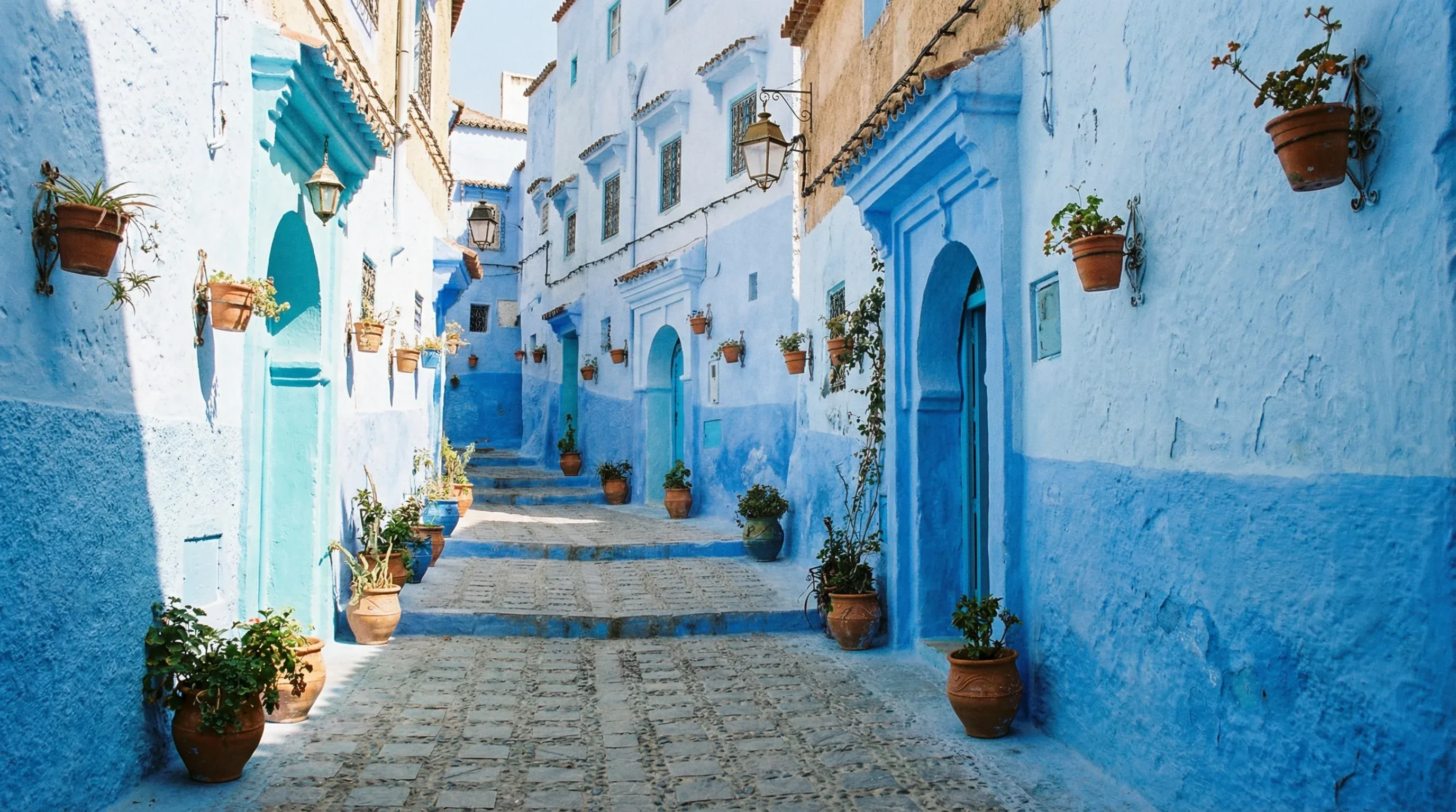 A narrow, winding street in Chefchaouen where the buildings, walls, and stairs are all painted in various shades of blue.