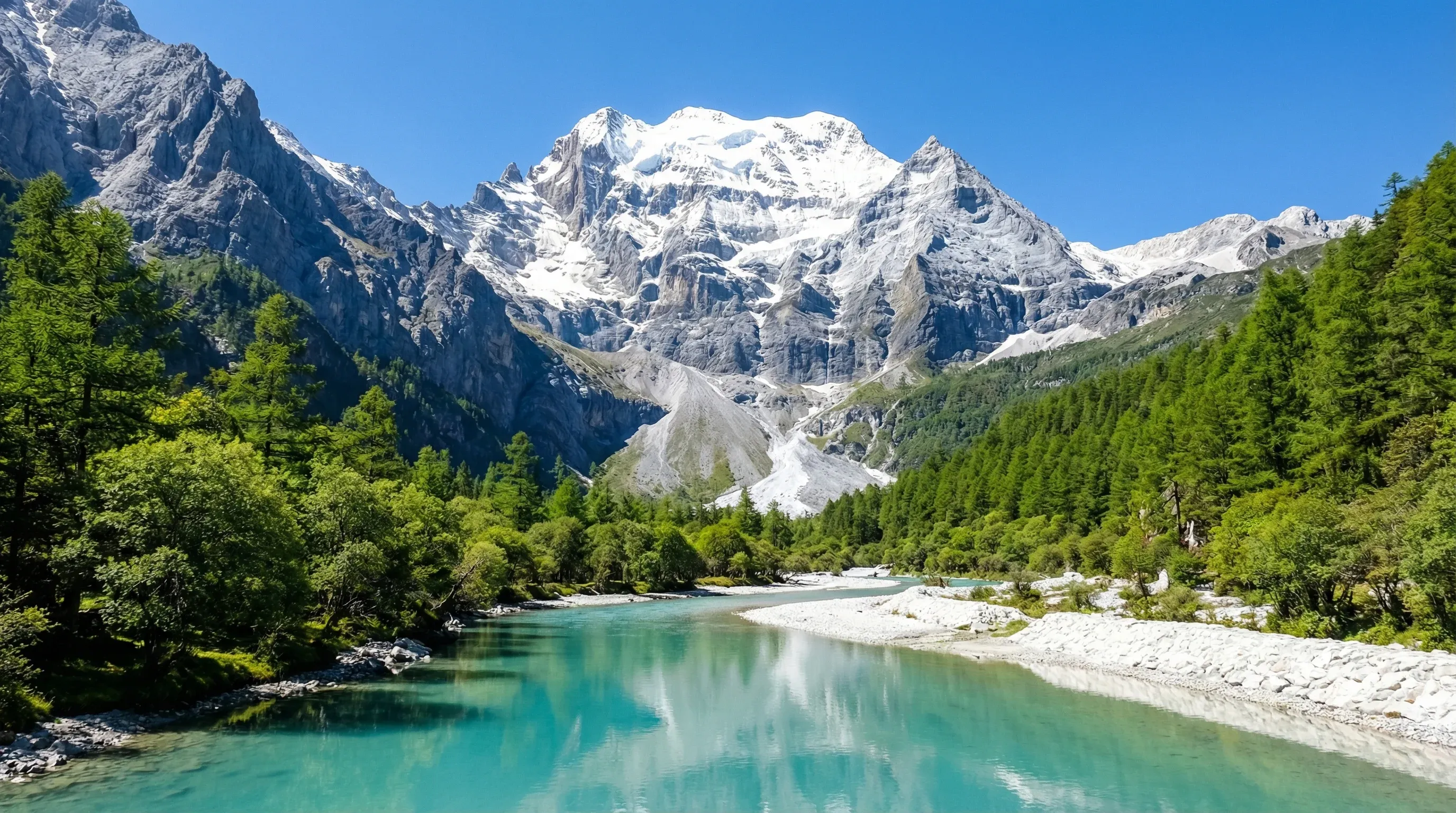 A turquoise river in a valley with the snow-capped Jade Dragon Snow Mountain peaks in the background.