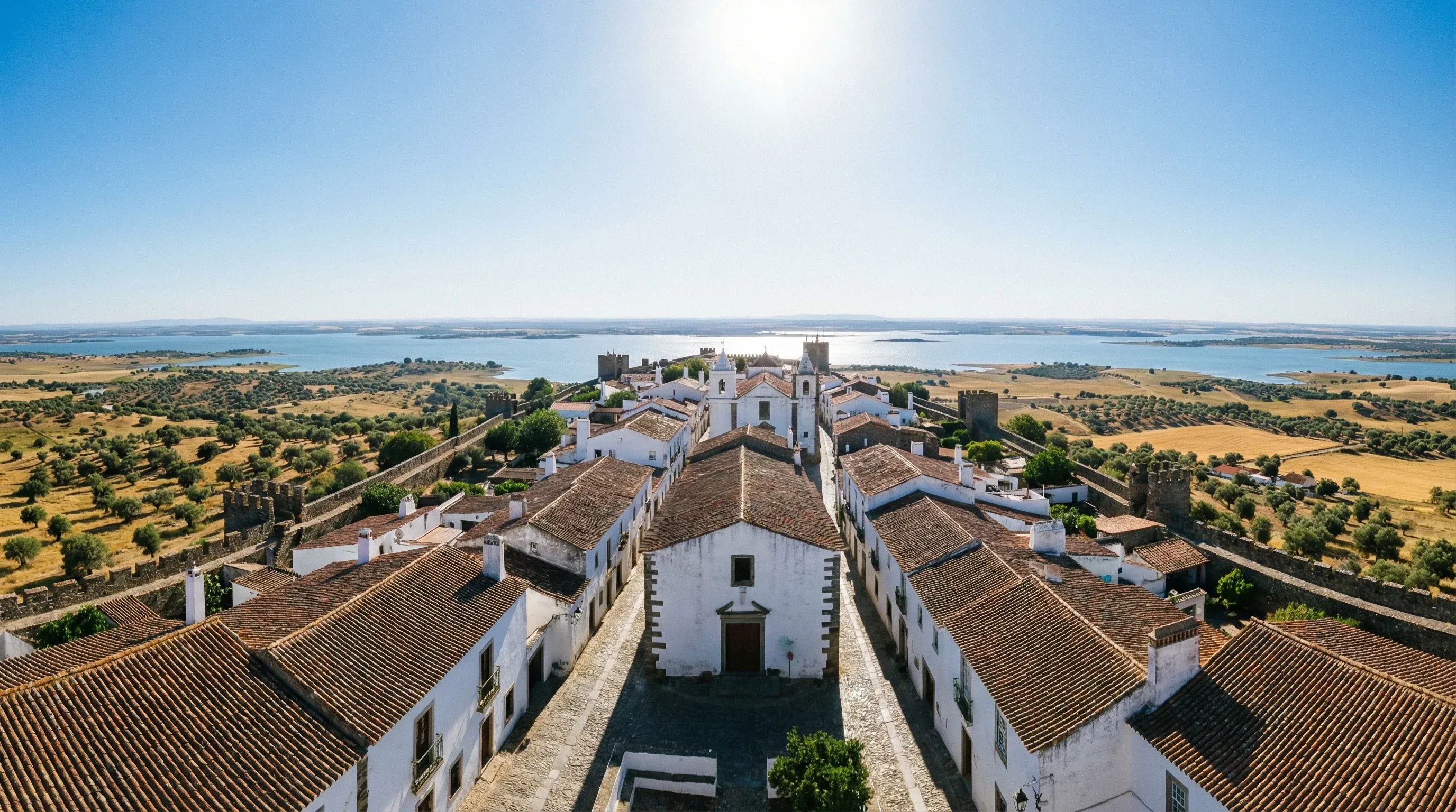 Whitewashed medieval village of Monsaraz overlooking the Alqueva Lake in Alentejo, Portugal, under a clear sky.