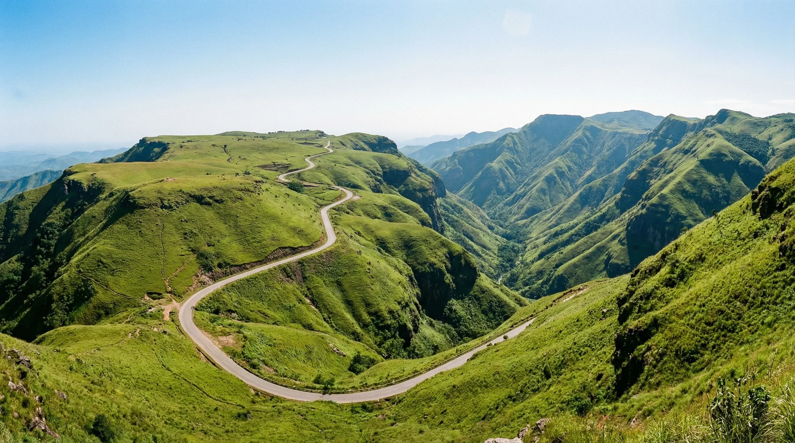 The rolling green mountains and winding roads of the Obudu Mountain Resort under a clear sky in southeastern Nigeria.