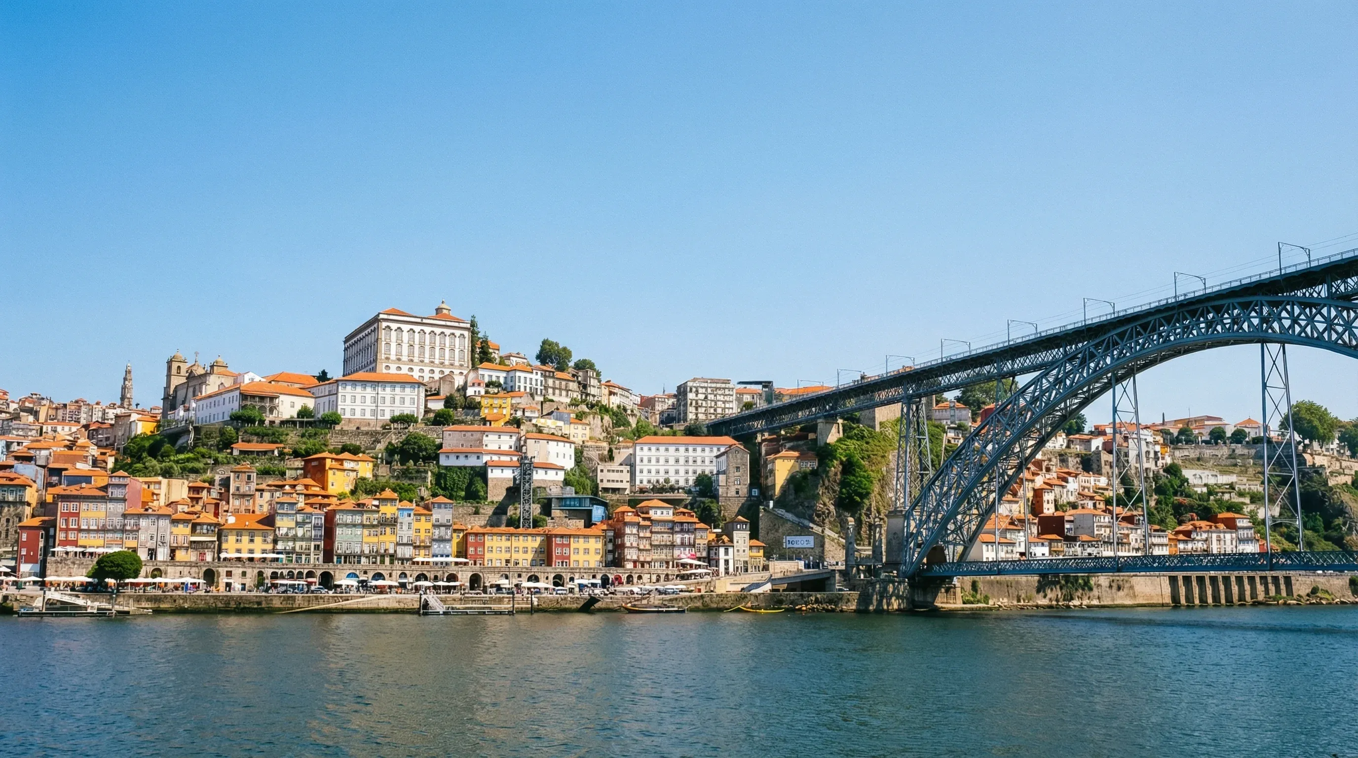 The iron Dom Luís I Bridge and the colorful Ribeira district houses along the Douro River in Porto.