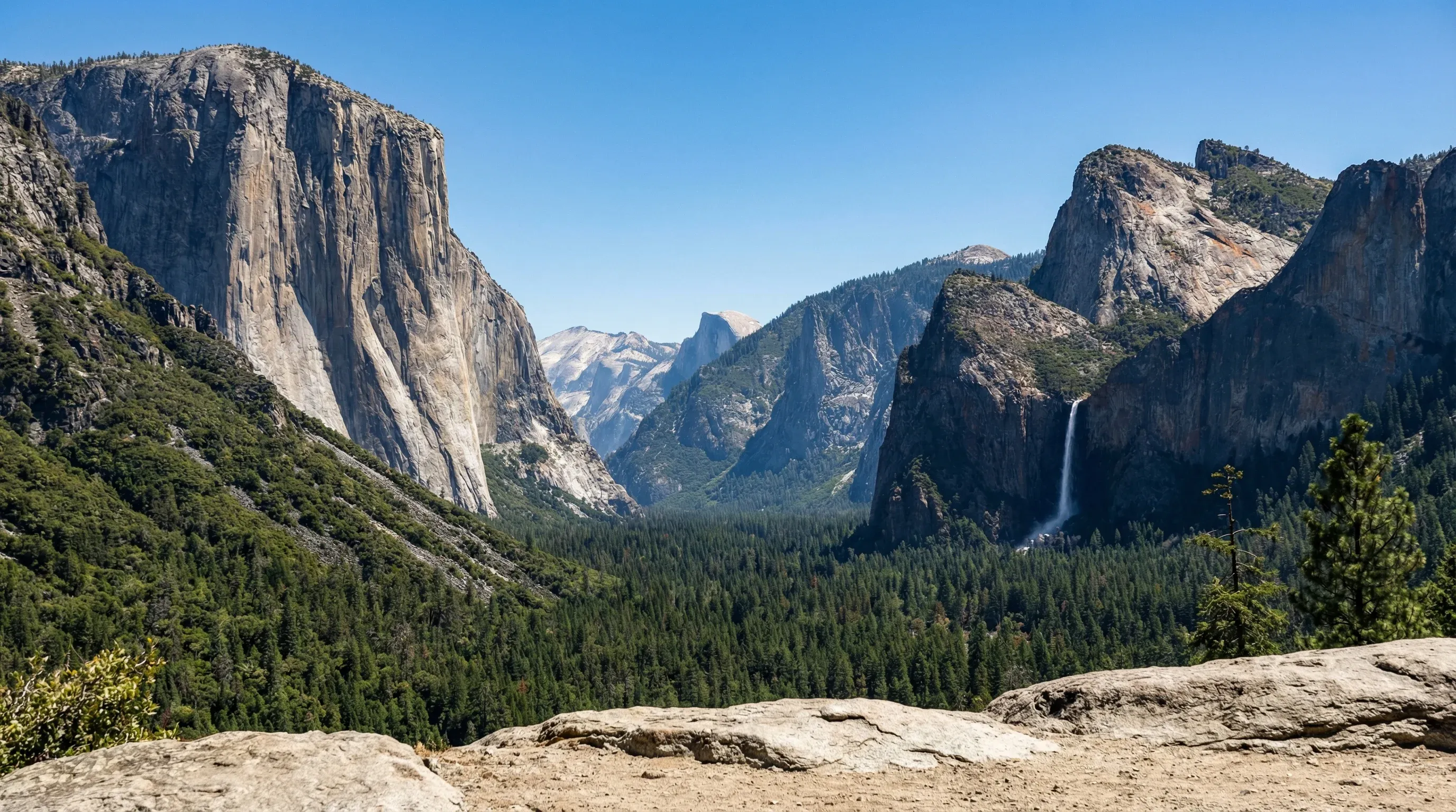 A wide landscape of Yosemite Valley showing El Capitan, Half Dome, and Bridalveil Fall in California.