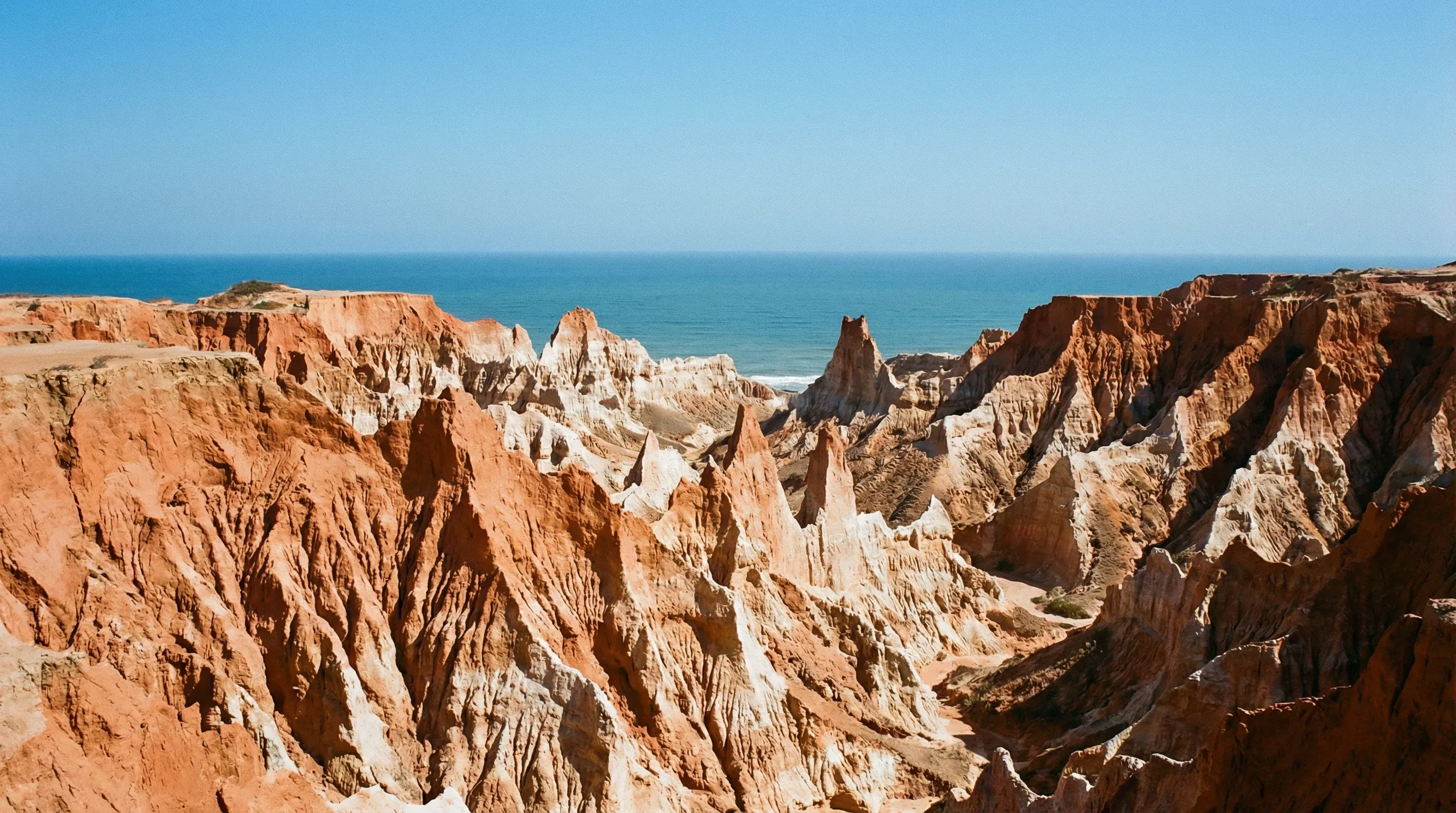 Eroded red and white clay cliffs and pinnacles of Miradouro da Lua overlooking the ocean in Luanda, Angola.