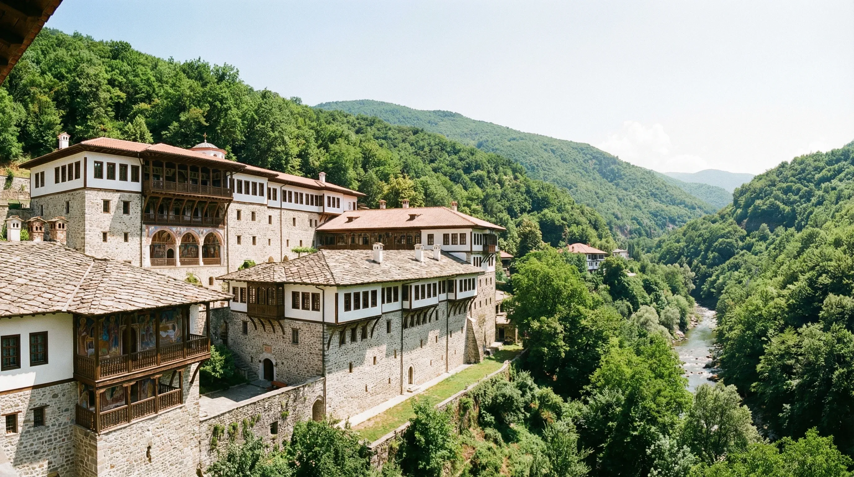 The traditional stone and wood buildings of Saint Jovan Bigorski Monastery on a forested mountain side in Mavrovo.