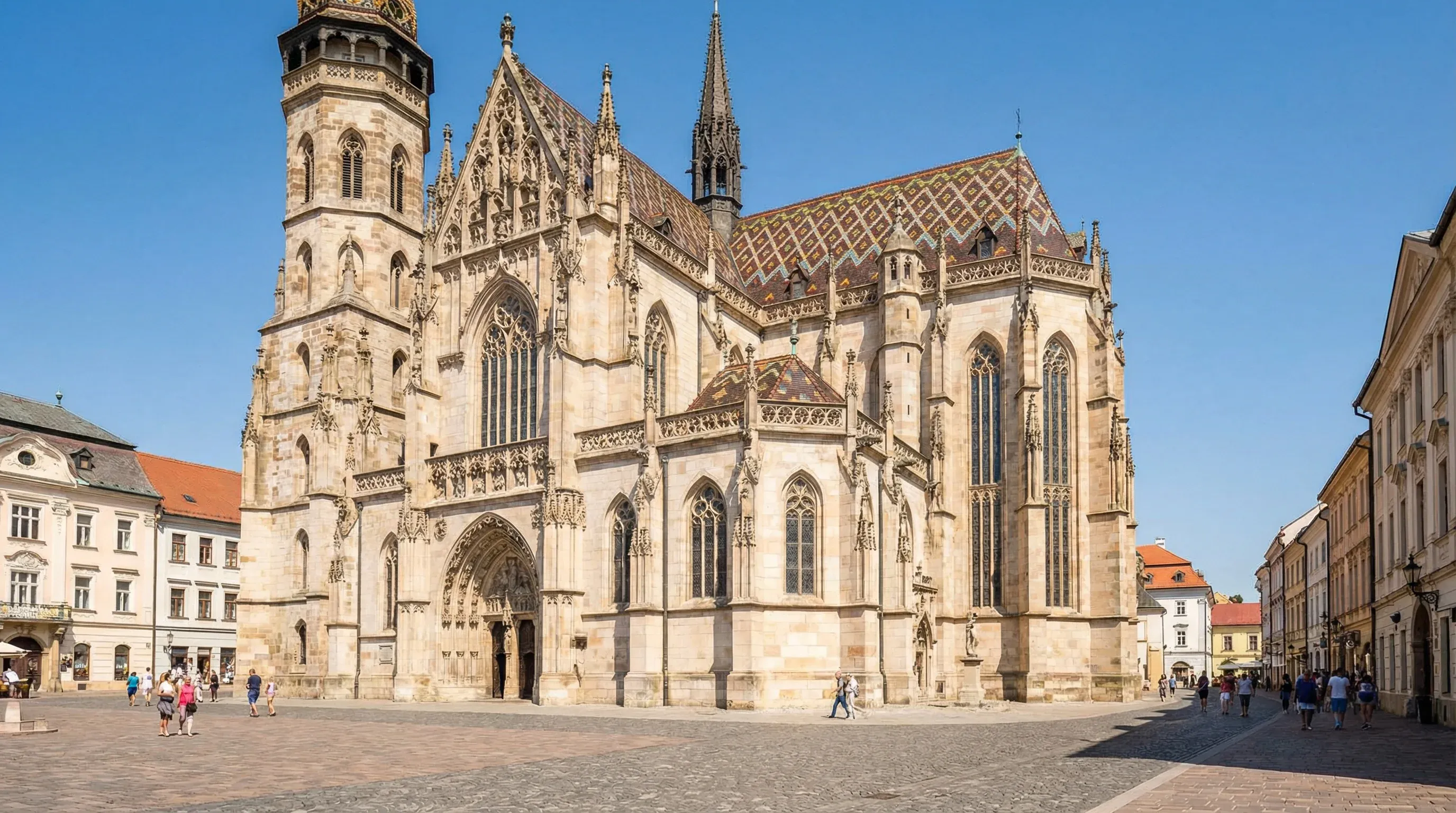 A large Gothic cathedral with intricate stone details and a tall tower in a city center square.