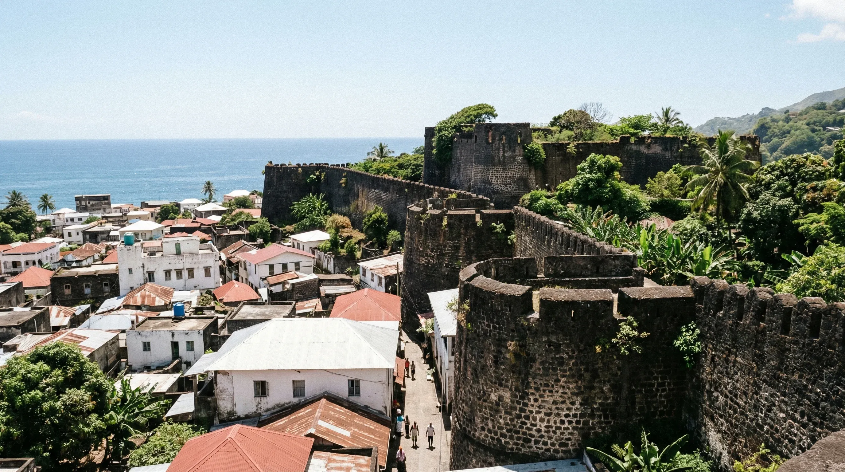 A high-angle view of the historic stone walls of the Mutsamudu Citadel overlooking the coastal town and harbor of Anjouan.
