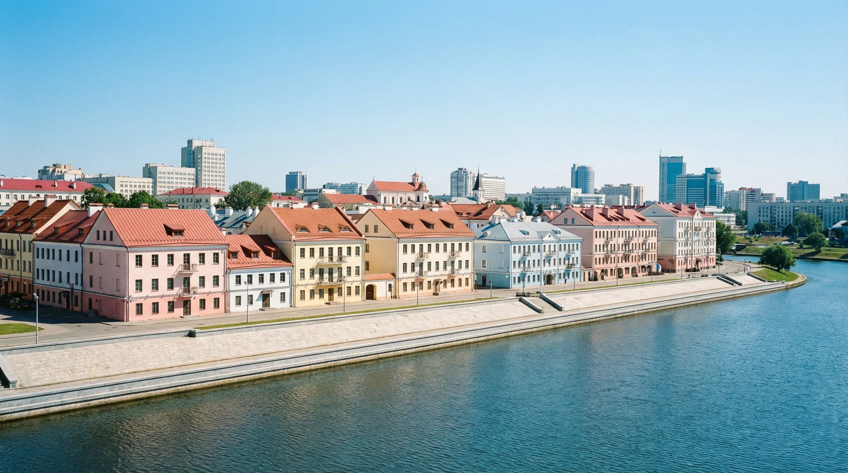 A row of historic colorful buildings with tiled roofs along the Svislach River embankment in Minsk.