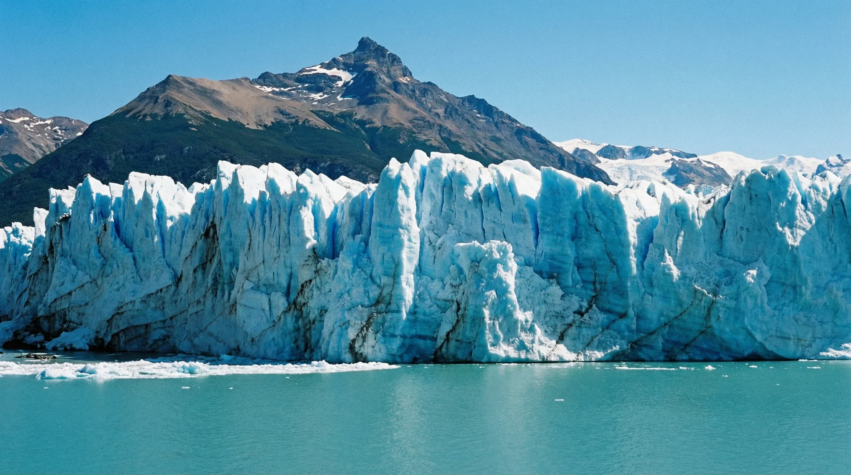 The massive blue ice wall of the Perito Moreno Glacier meets the water of Lago Argentino.