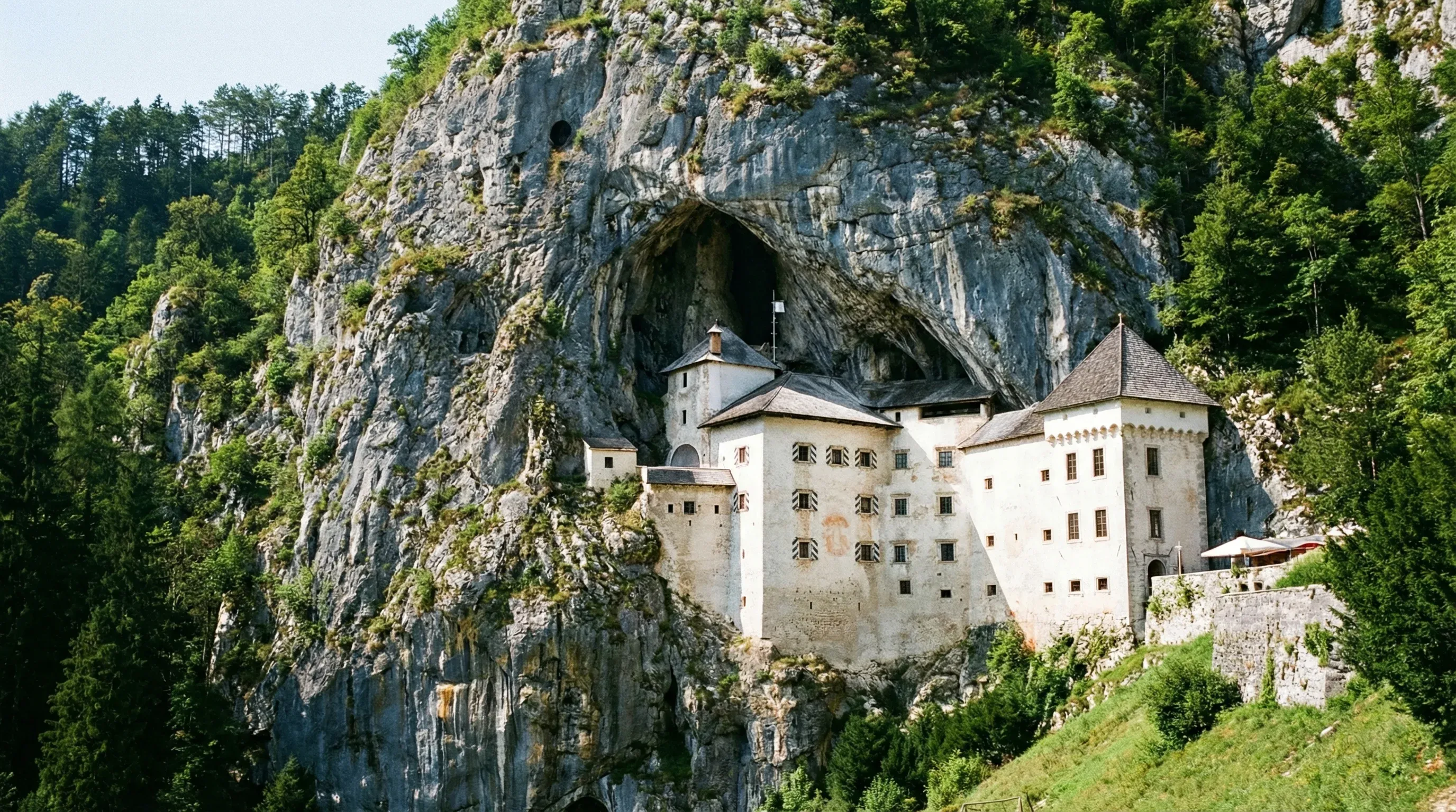 Predjama Castle, a Renaissance fortress built into the mouth of a limestone cave on a vertical cliff side.