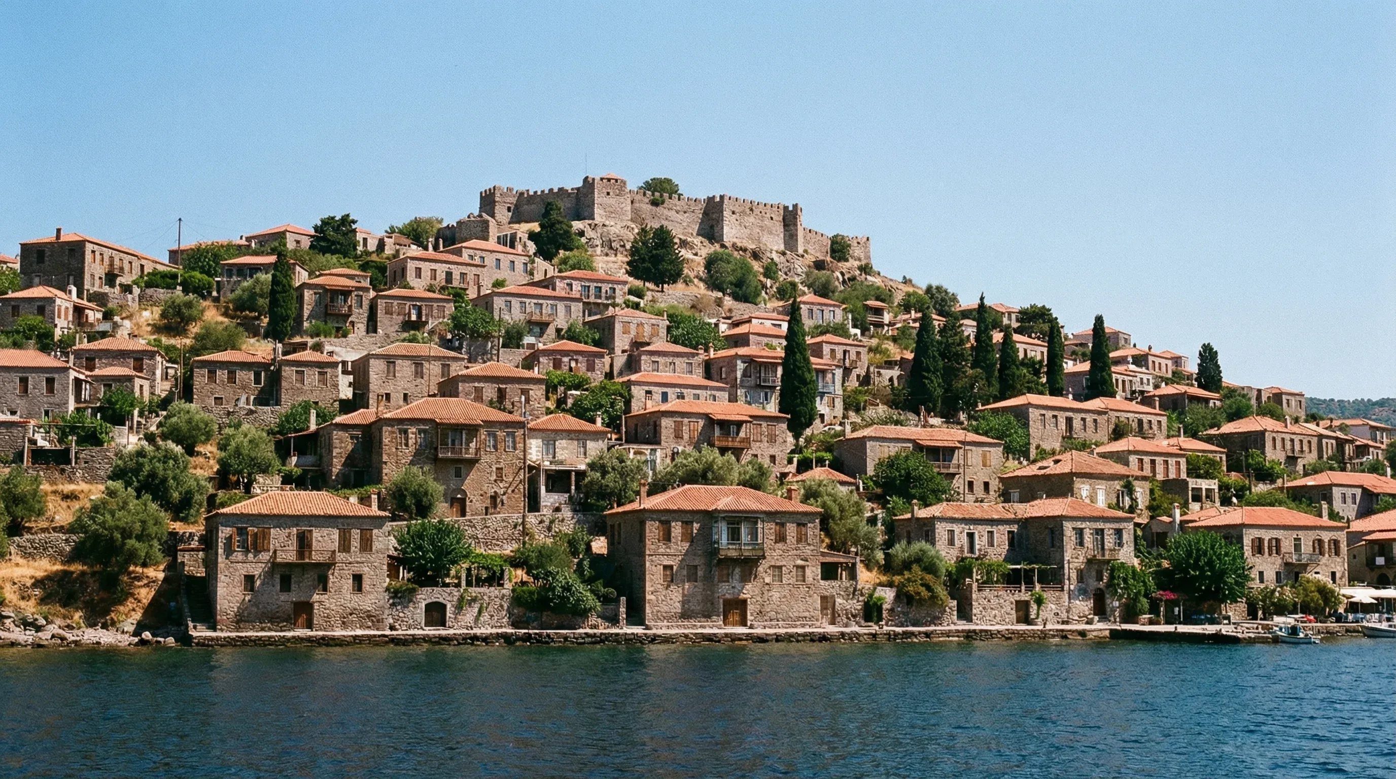 Traditional stone houses and a medieval castle on a hillside overlooking the sea in Molyvos.