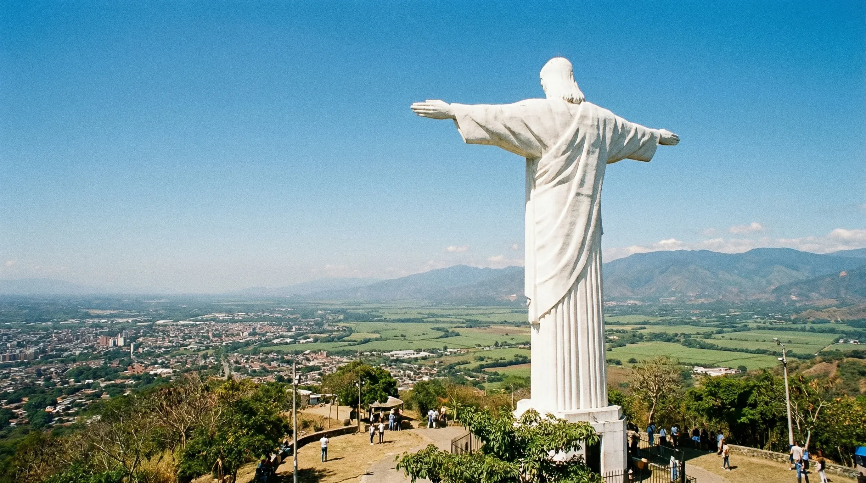The large white Cristo Rey statue on a hilltop overlooking the city of Cali and the surrounding valley floor.