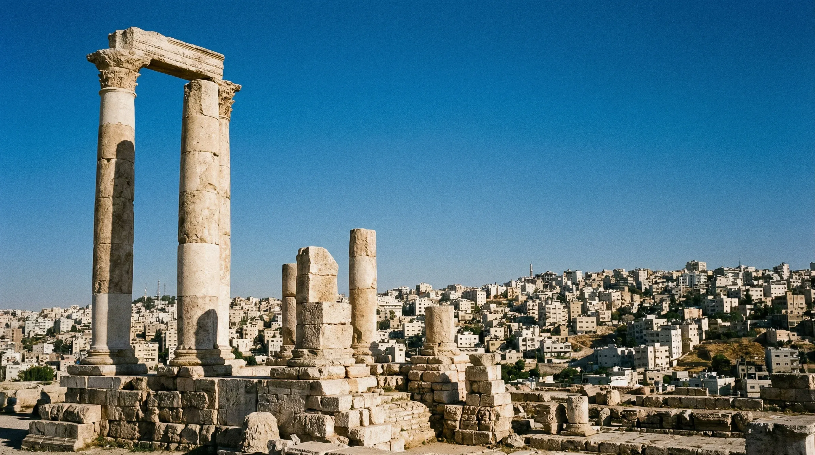 The ancient stone columns of the Temple of Hercules at the Amman Citadel overlook the dense urban hills of Jordan's capital city.