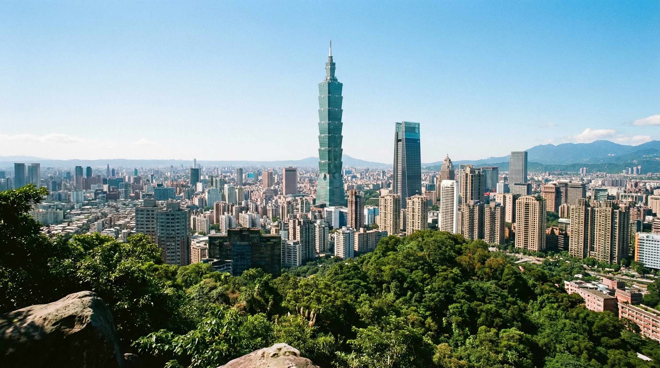 The Taipei 101 skyscraper rising above the city skyline of Taipei as seen from a mountain viewpoint.
