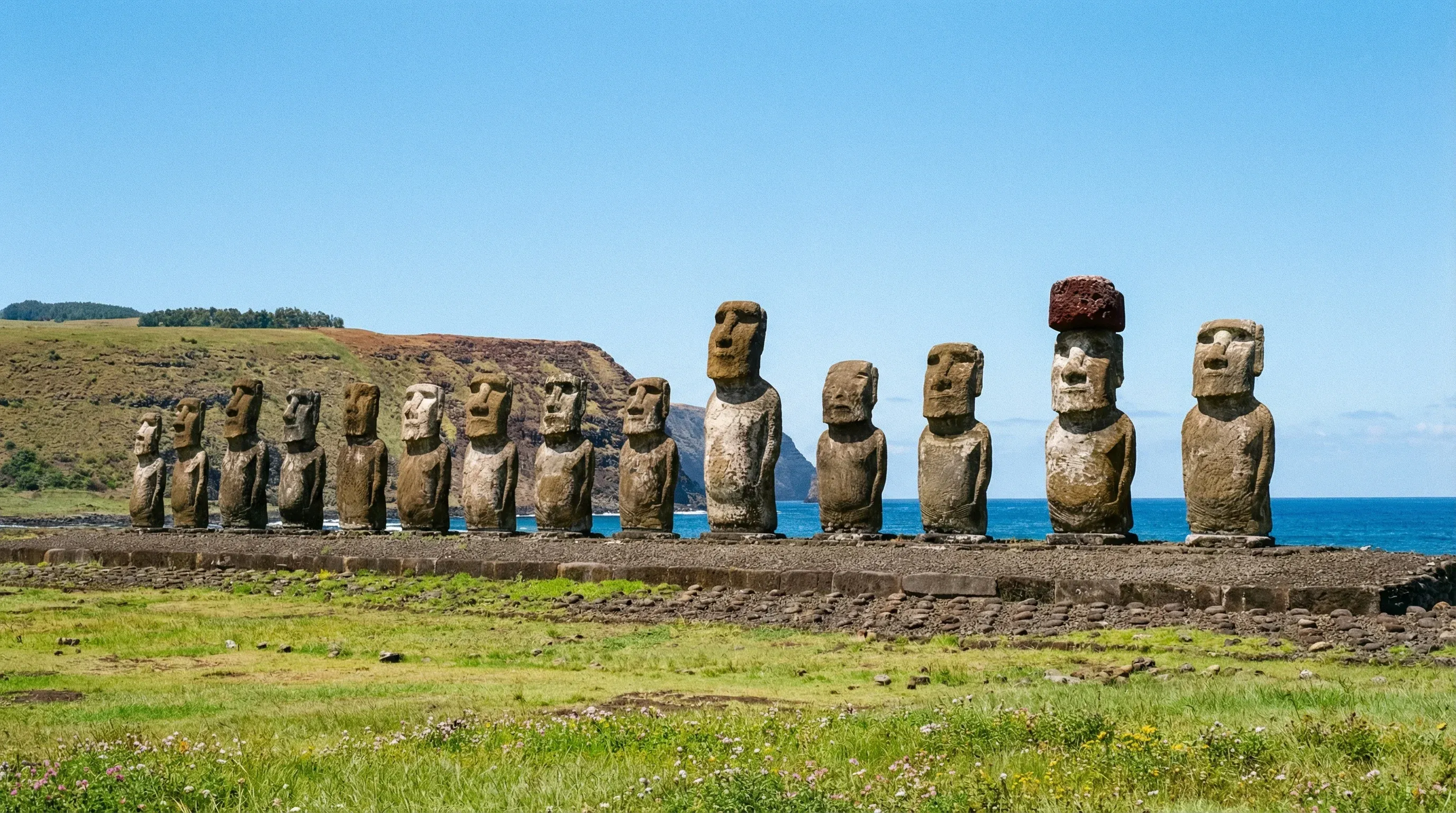 Fifteen large stone Moai statues standing on a platform at Ahu Tongariki against the Pacific Ocean.