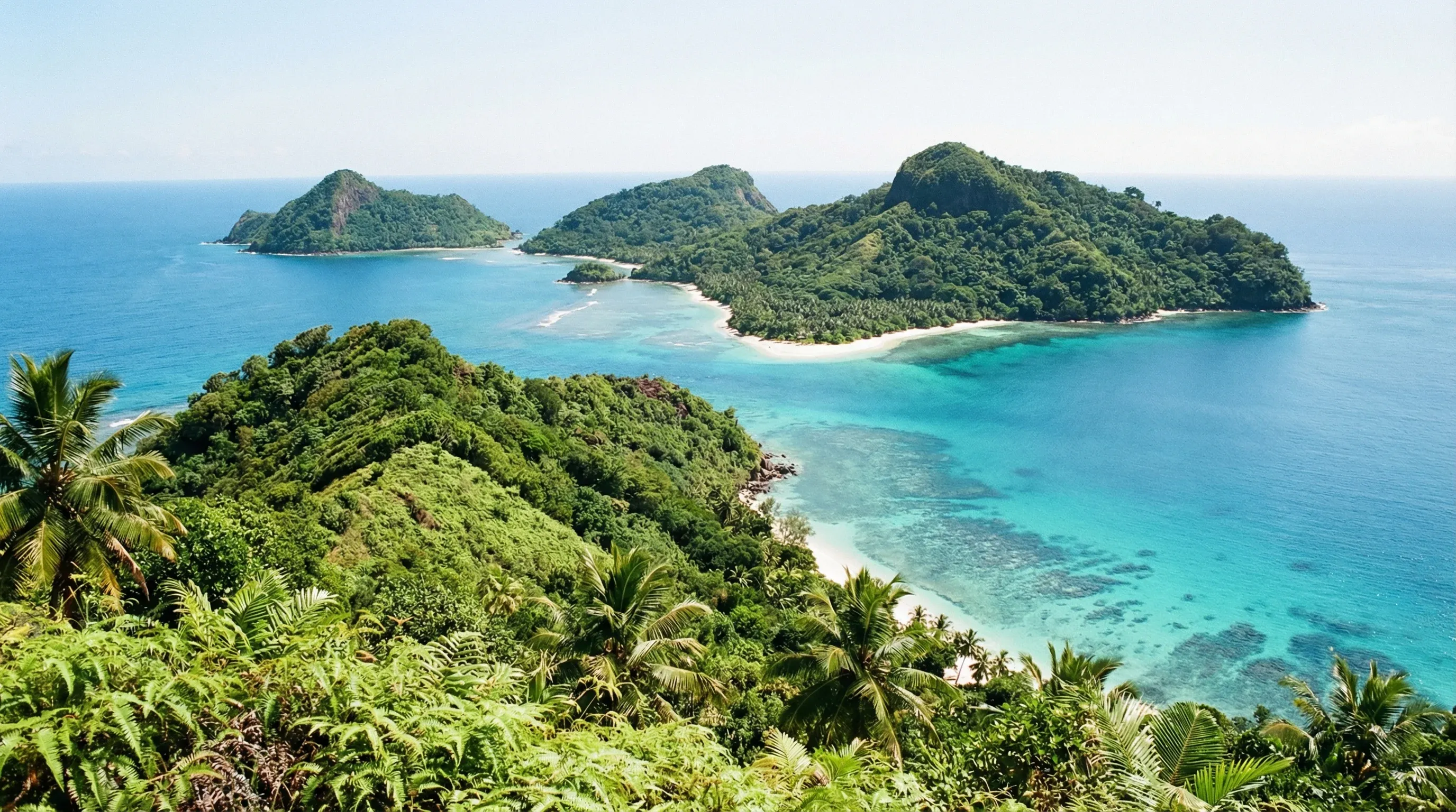 A panoramic view of several small, forested volcanic islands surrounded by clear turquoise water in the Mohéli Marine Park.