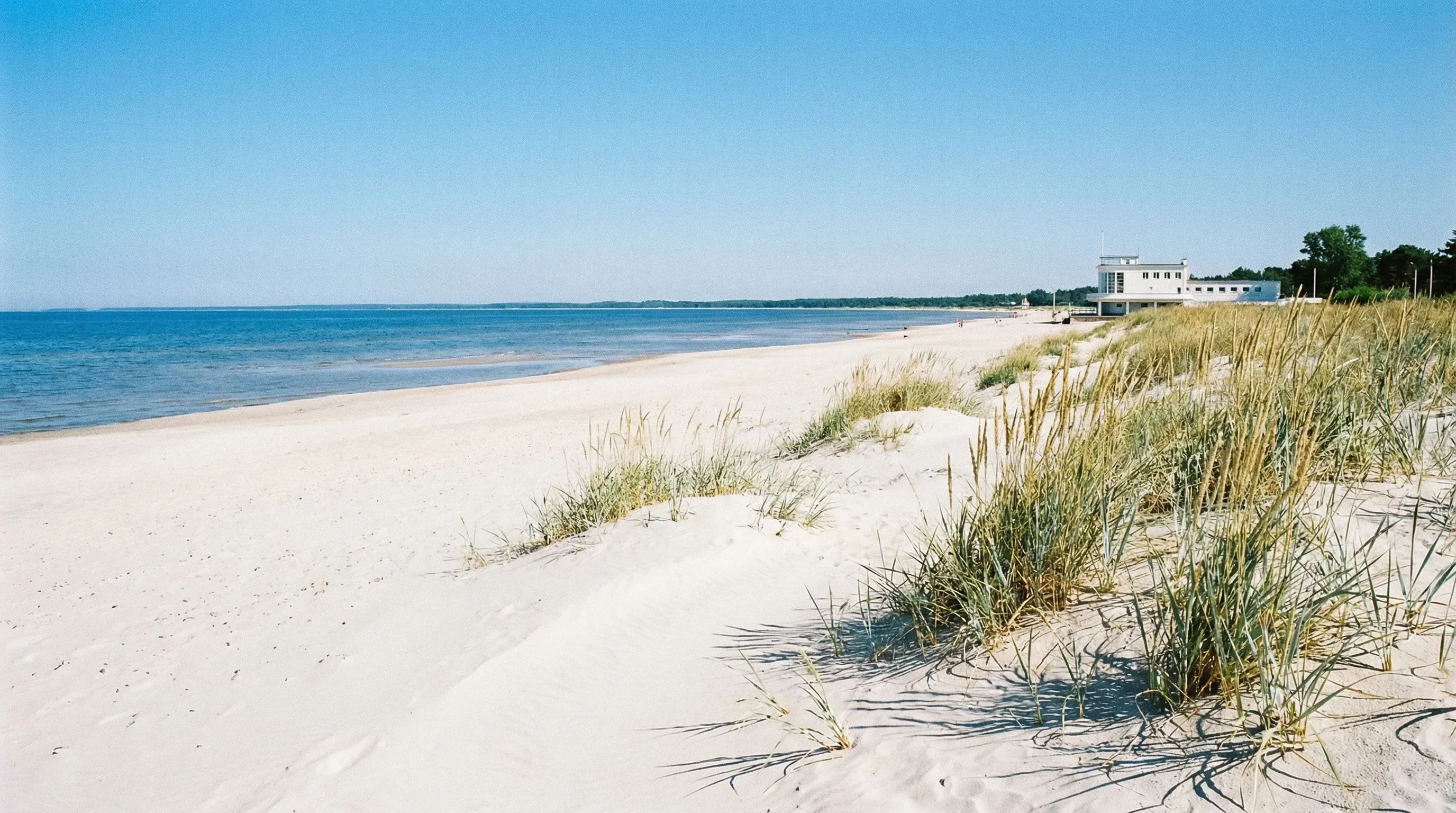The white sandy shoreline of Pärnu Beach and the Baltic Sea under a clear midday sky.