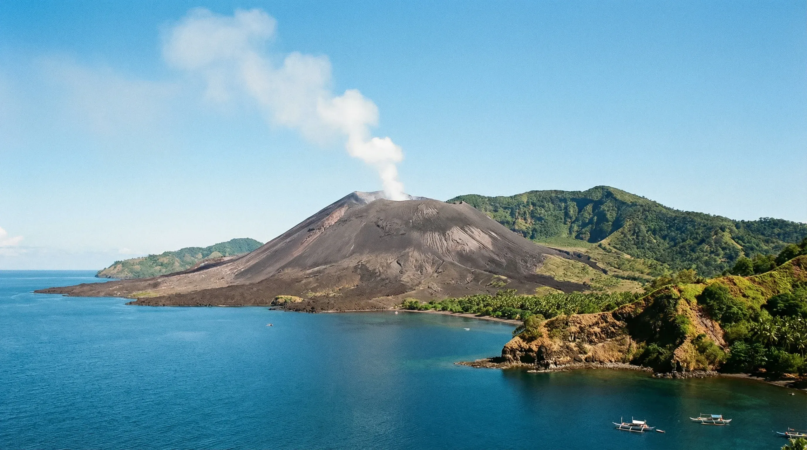 Mount Tavurvur volcano with its ash-covered slopes rising above the blue waters of Simpson Harbour in Kokopo, East New Britain.