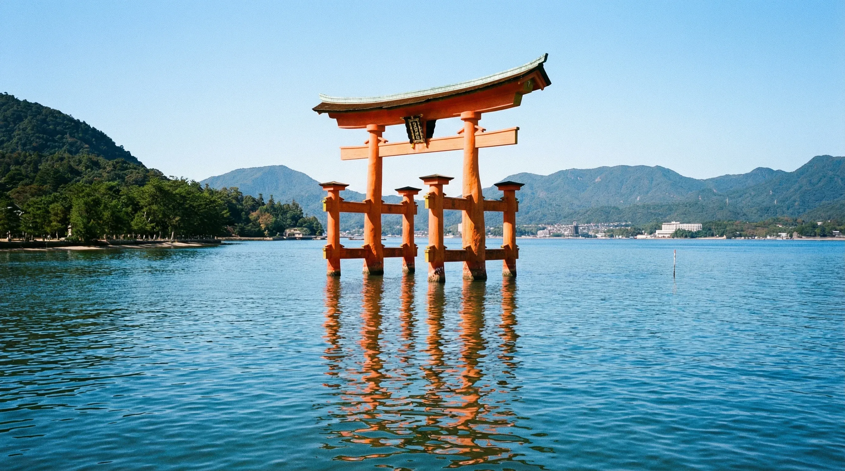 The vermilion Great Torii Gate of Itsukushima Shrine standing in the blue sea at Miyajima.